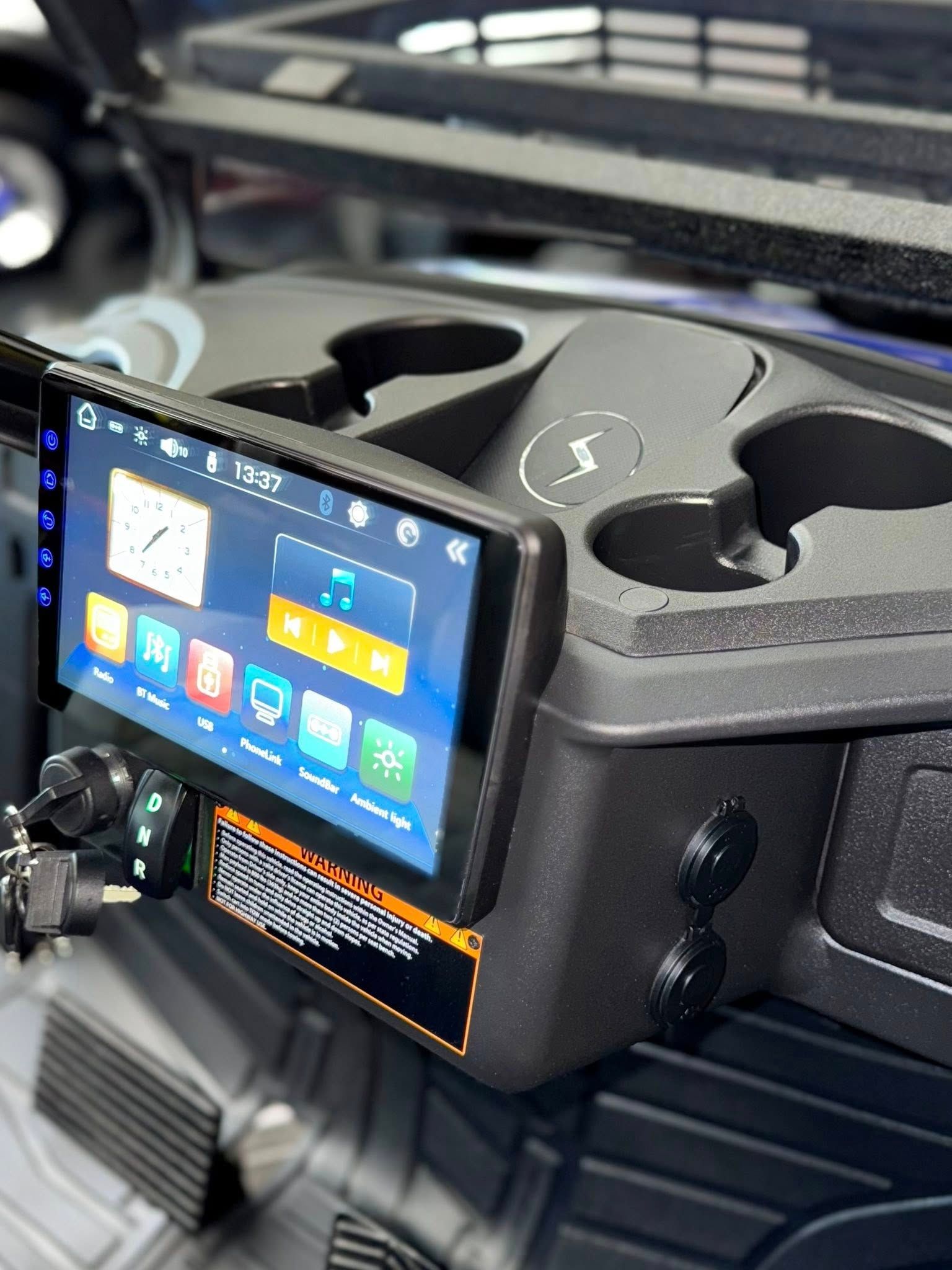 Golf cart console with touchscreen display, cup holders, and power outlets.