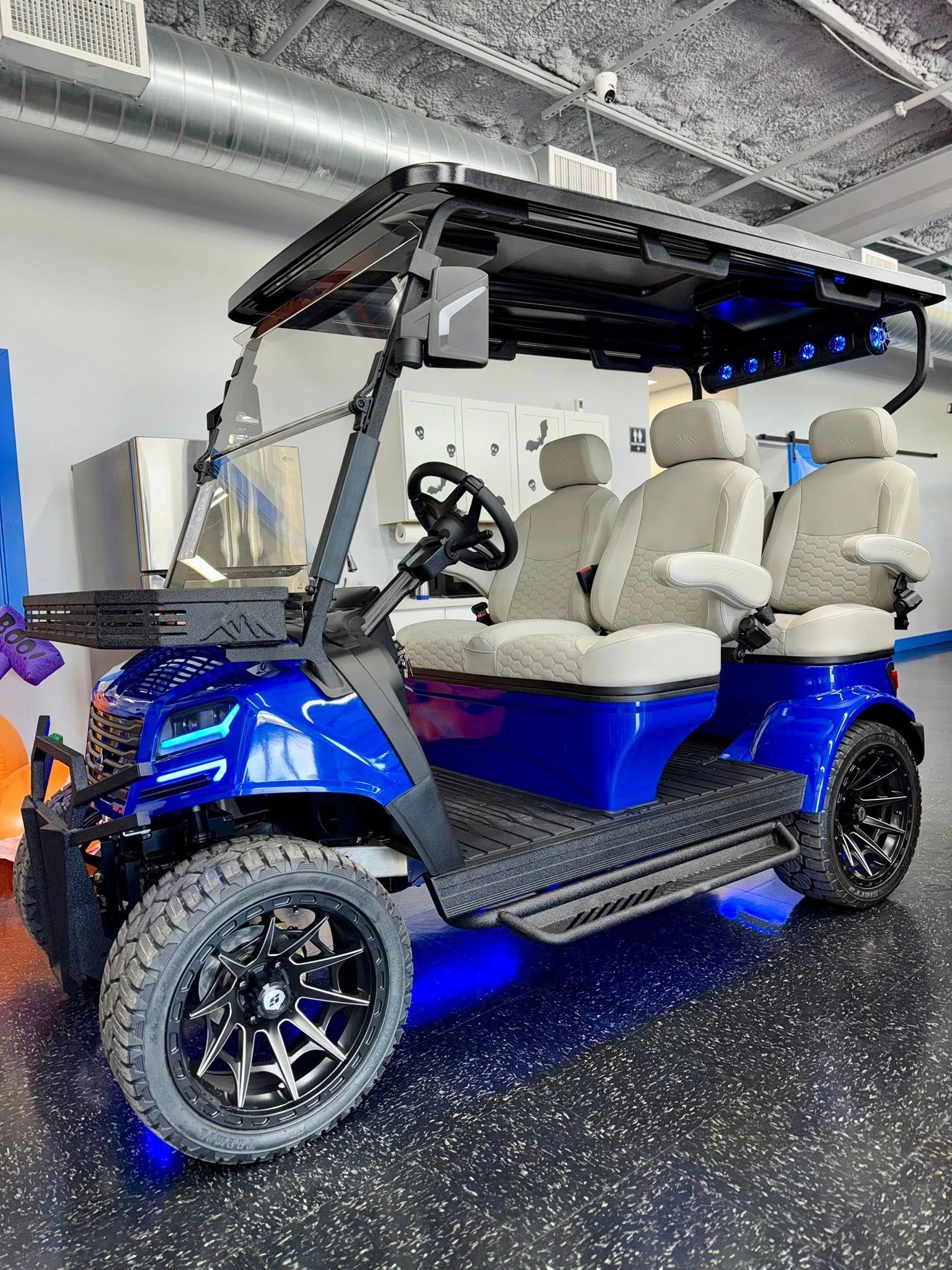 Blue golf cart with black accents and off-road tires, four seats.