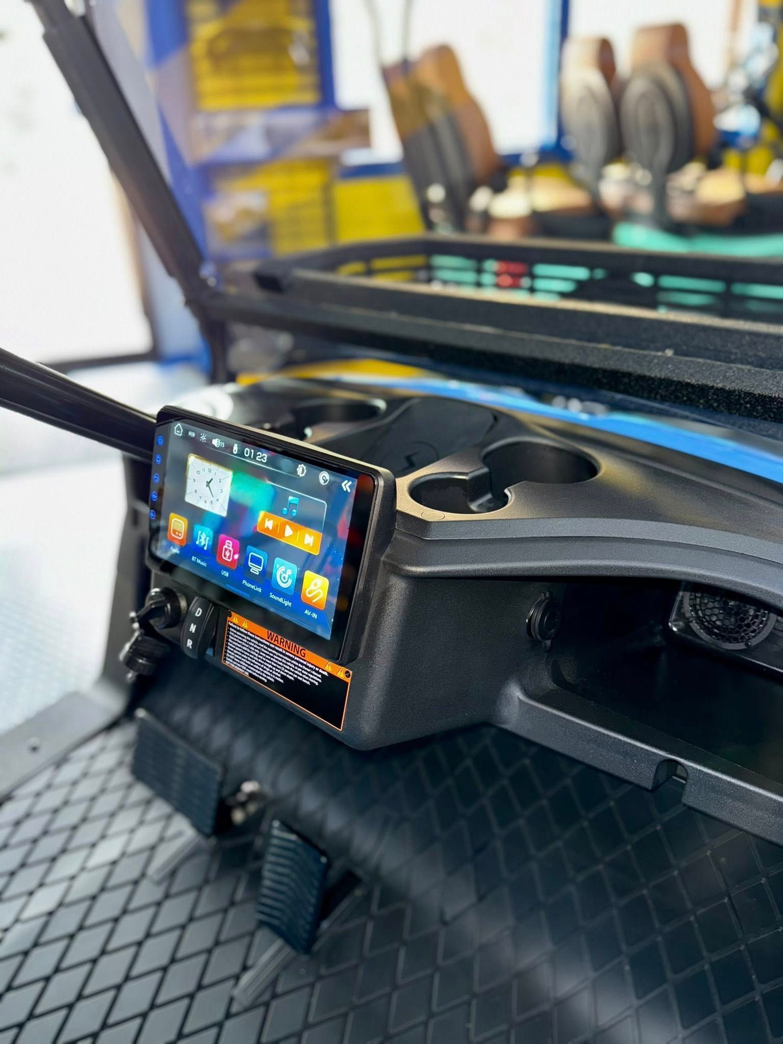 Golf cart dashboard with a touchscreen display, cup holders, and controls. Black and blue accents.
