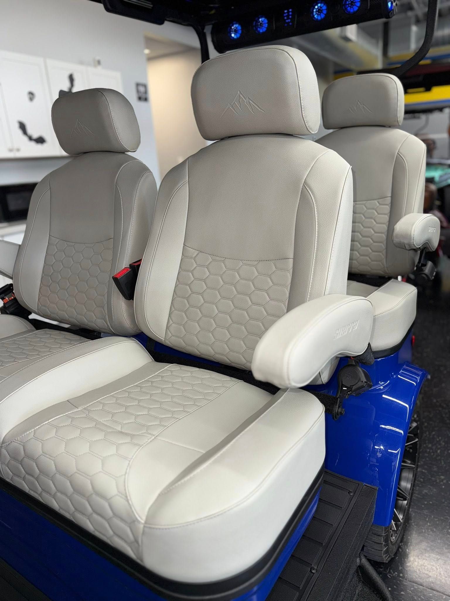 Blue golf cart interior with light gray and white seats, armrests, and a patterned design.