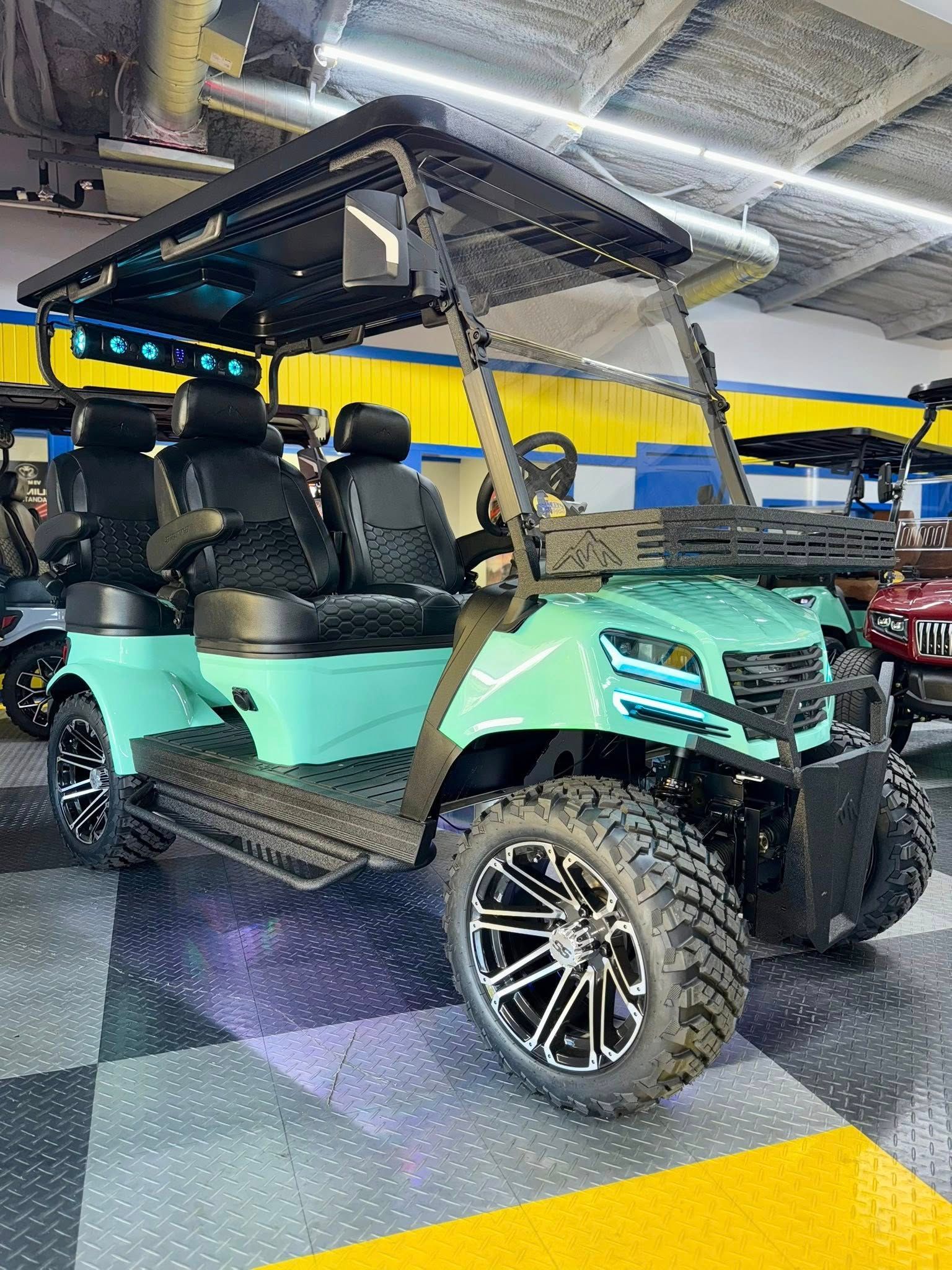 Mint green golf cart with black accents and off-road tires, parked indoors.