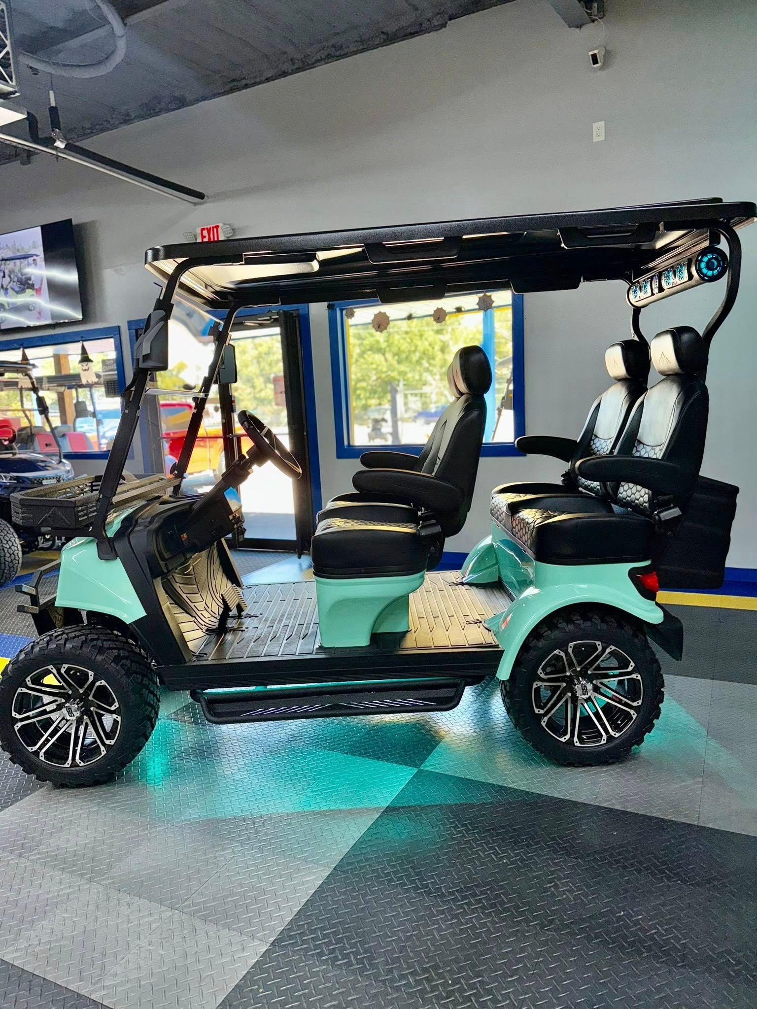 Mint green golf cart with black accents, custom wheels, and LED lights.