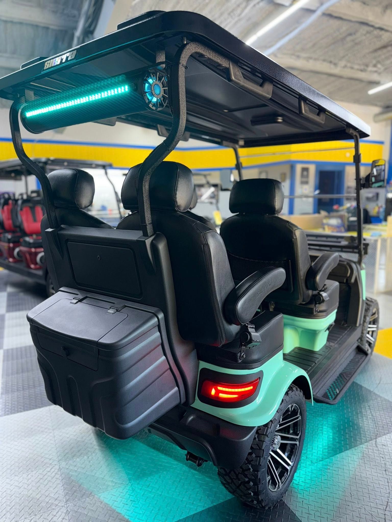 Mint green golf cart with black accents and custom LED lighting in a garage setting.