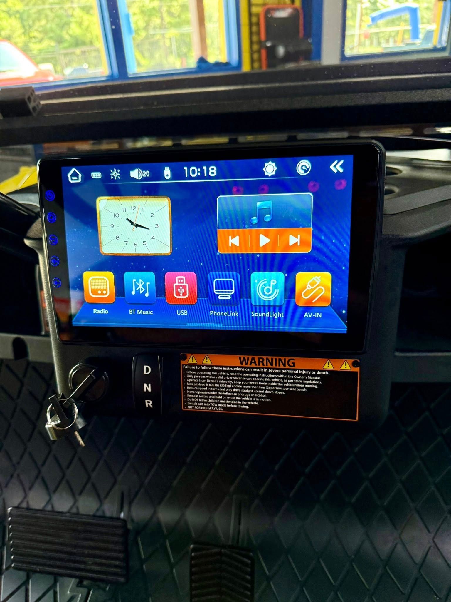 Car stereo with touchscreen interface displaying music controls and app icons.