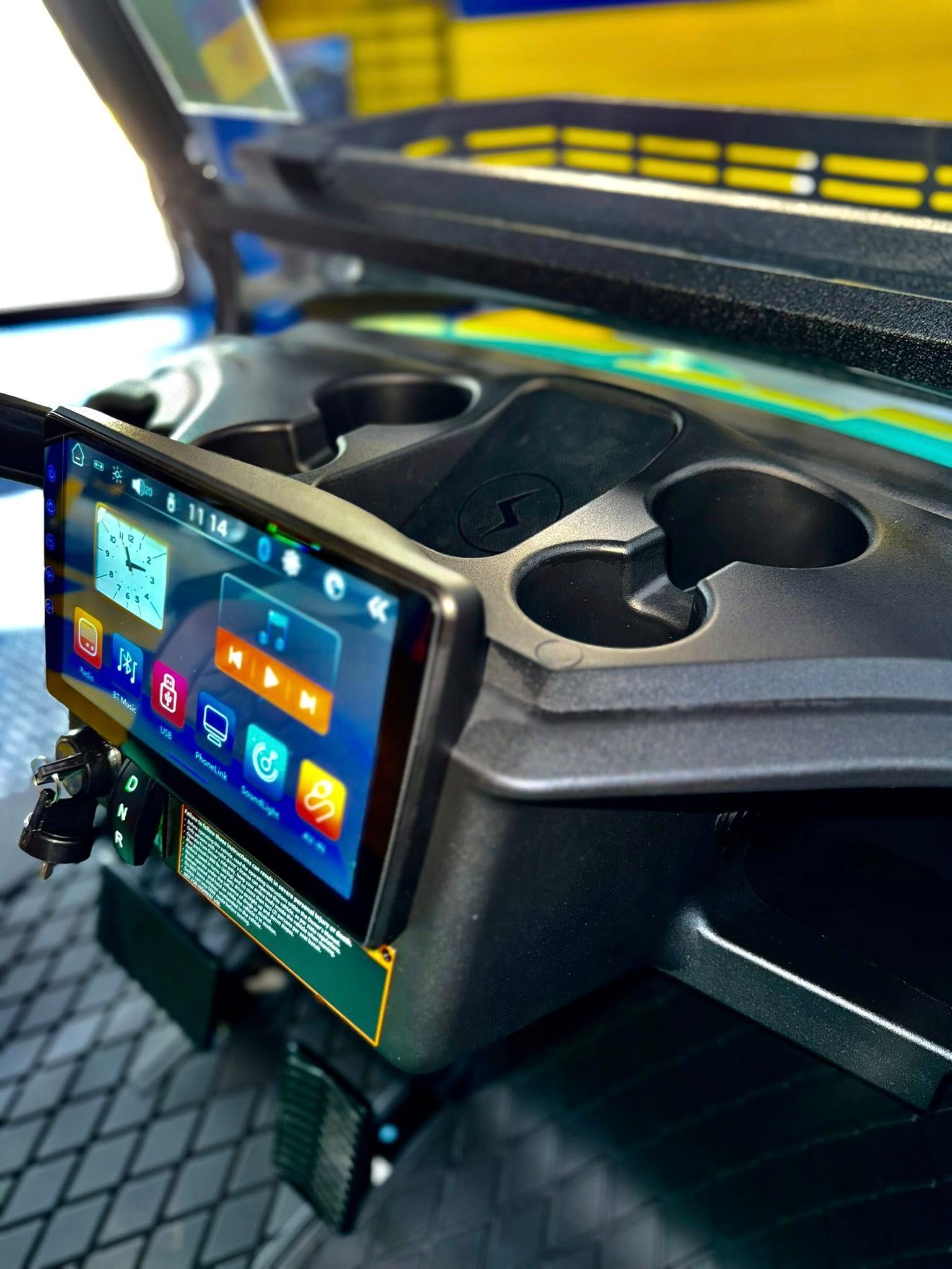Golf cart dashboard with a touchscreen display, cup holders, and controls.