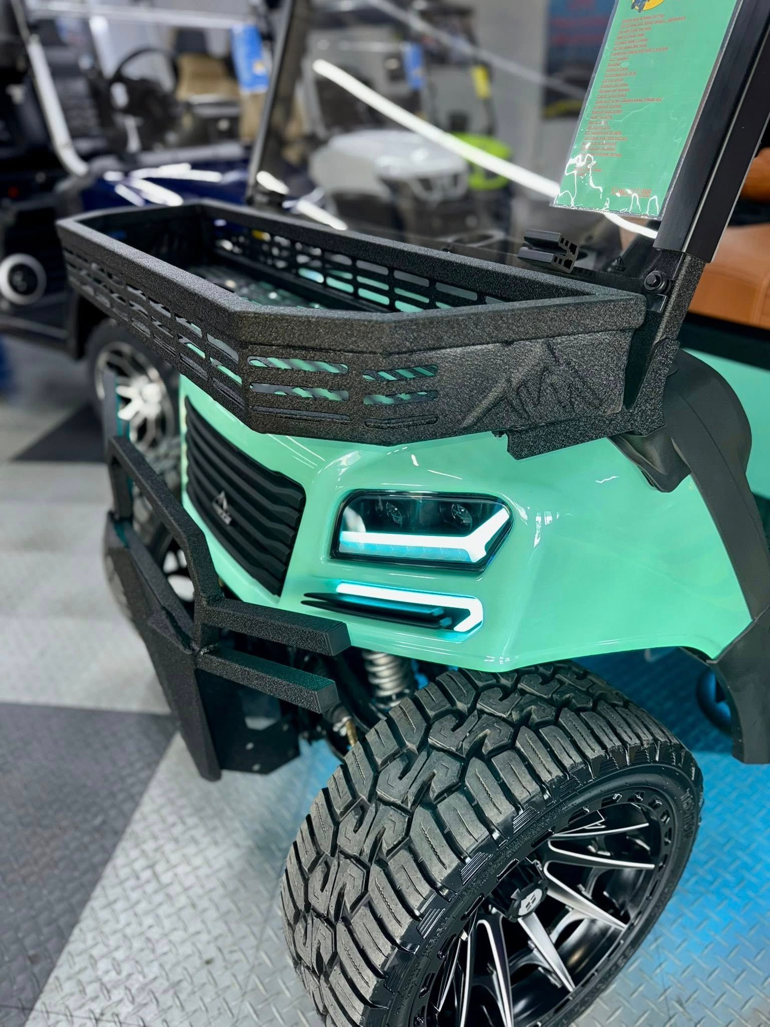 Green golf cart with black basket, bumper, and tires.