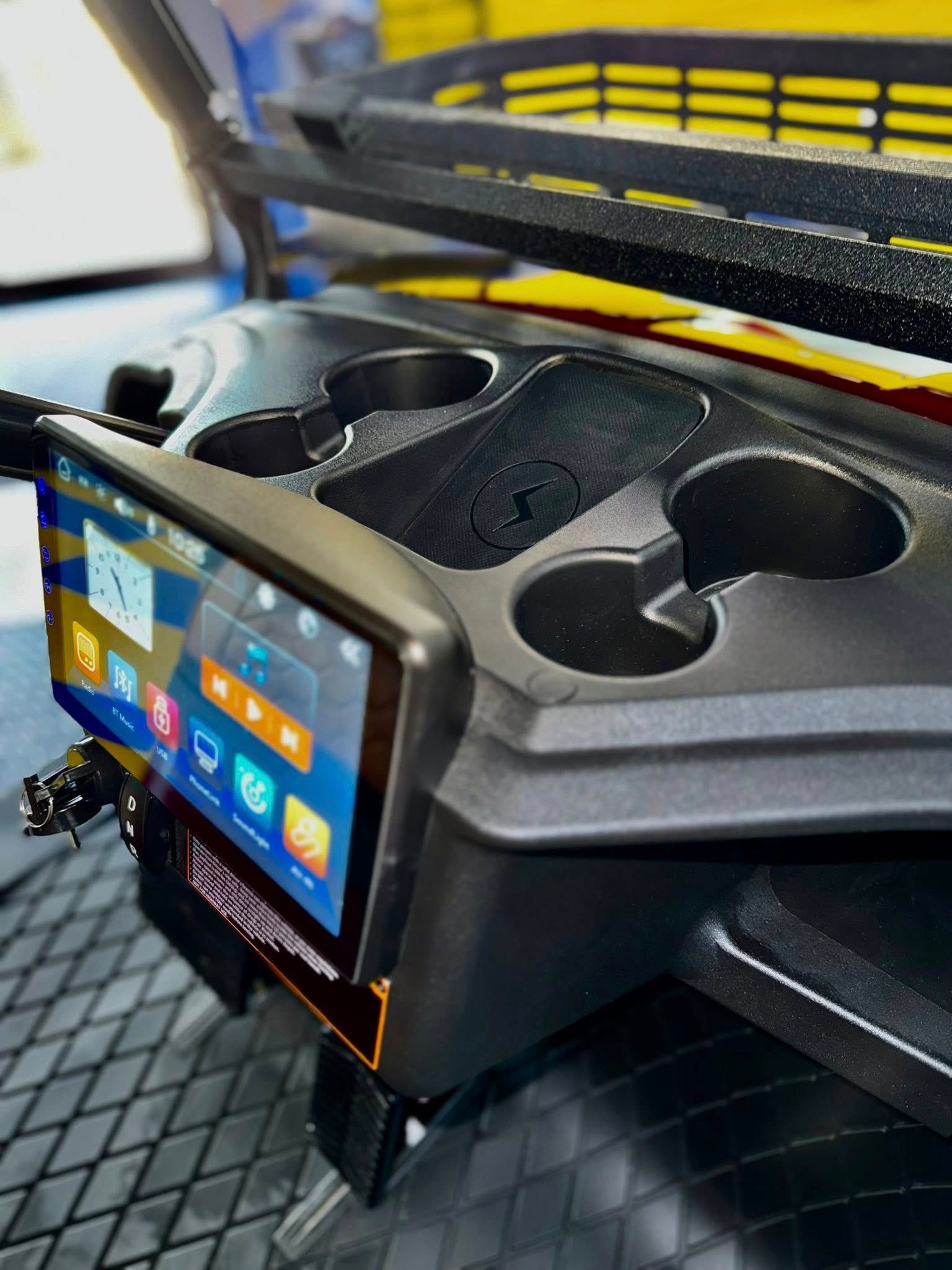 Golf cart console with a tablet screen, cup holders, and back support.