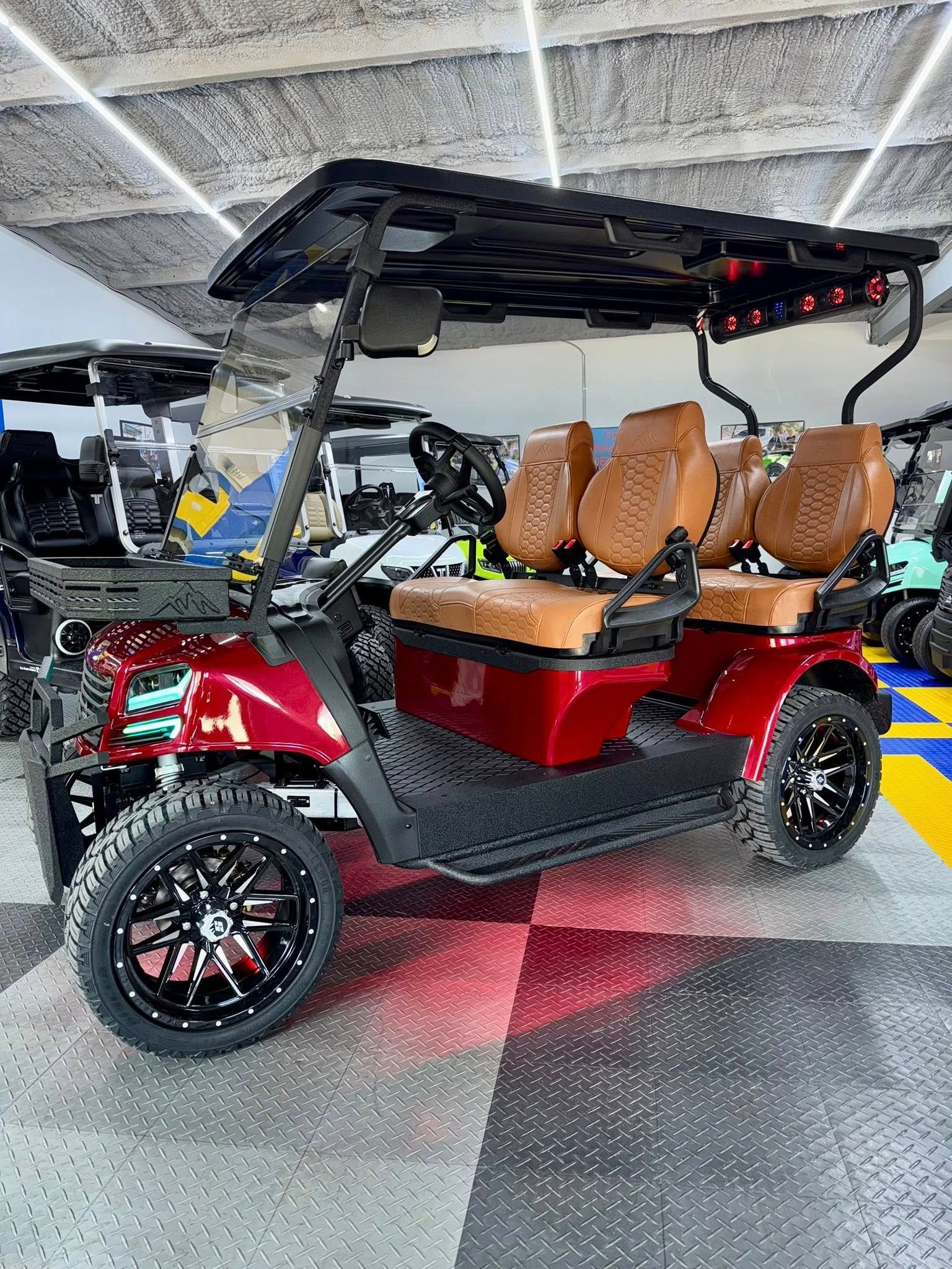 Red golf cart with black accents and tan seats, indoors under fluorescent lights.