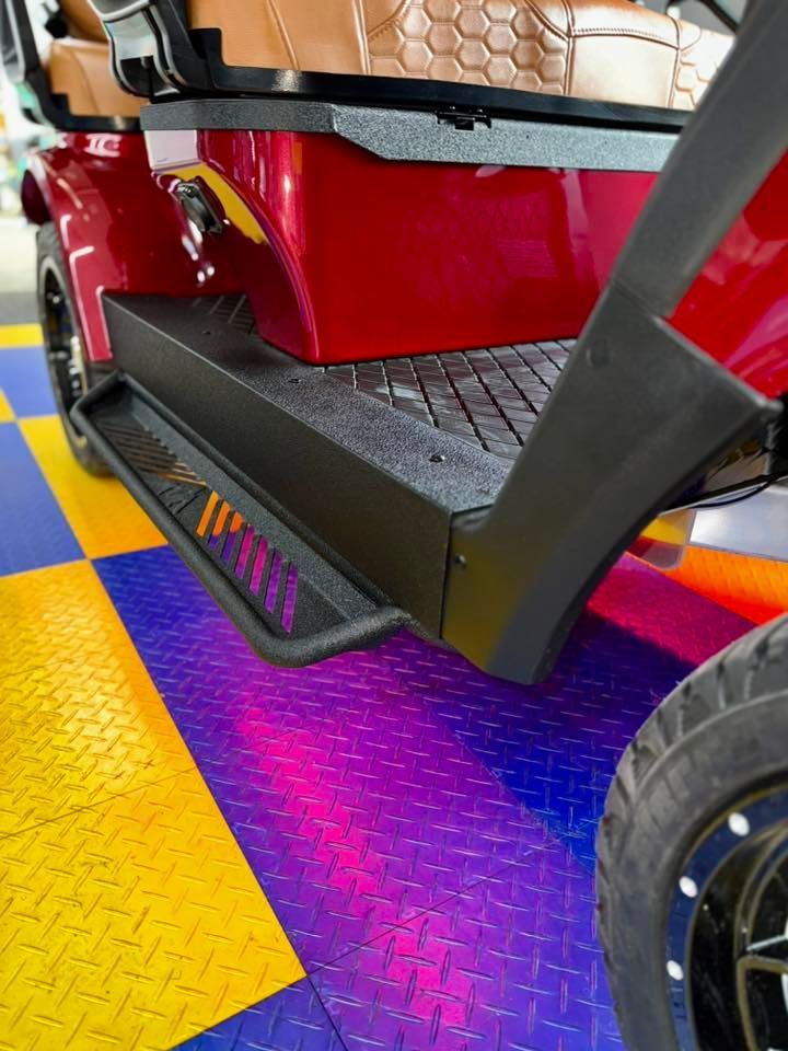 Red golf cart with black step and colorful diamond-patterned flooring.