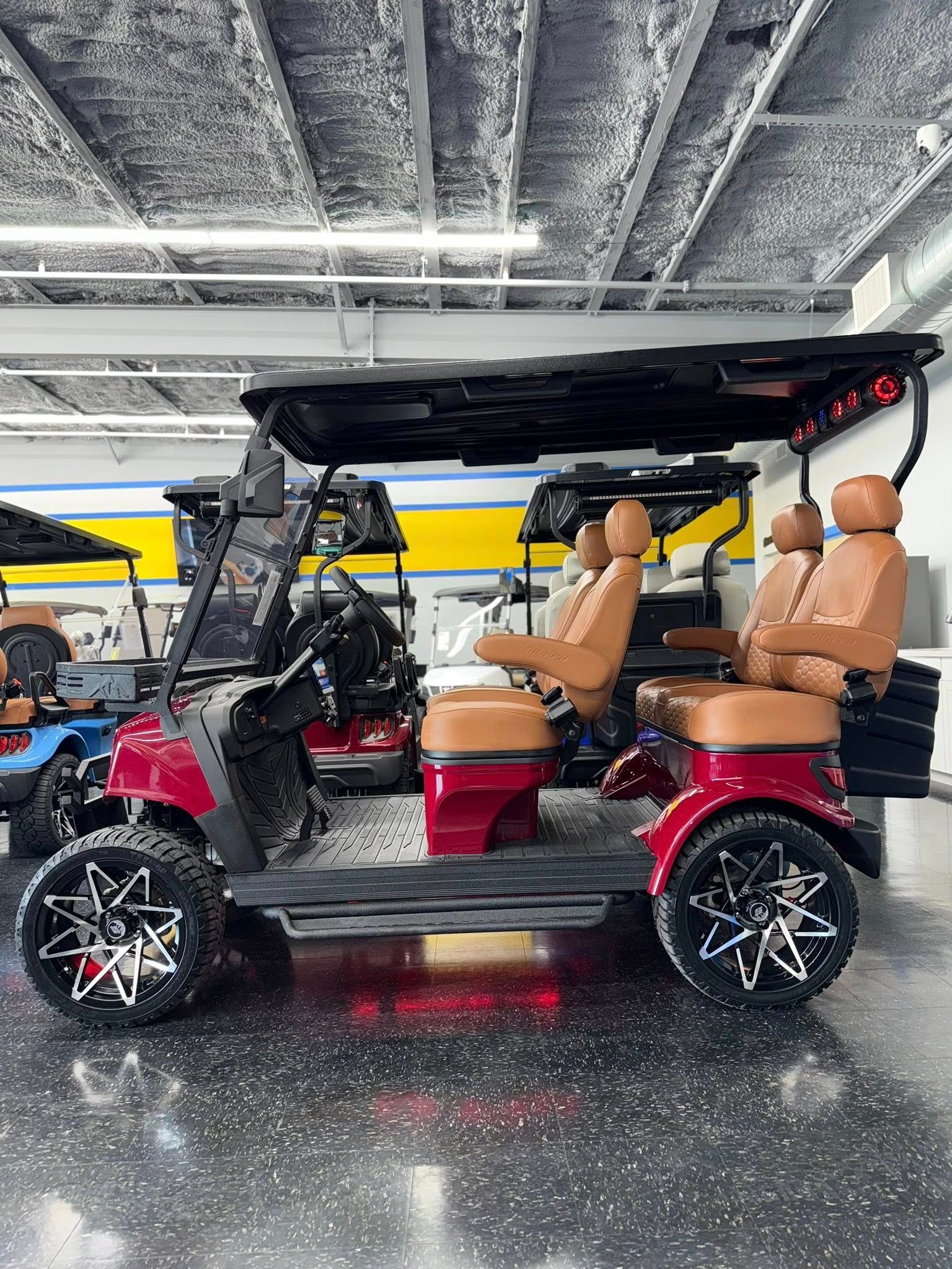 Red custom golf cart with brown leather seats, black roof, in a showroom.