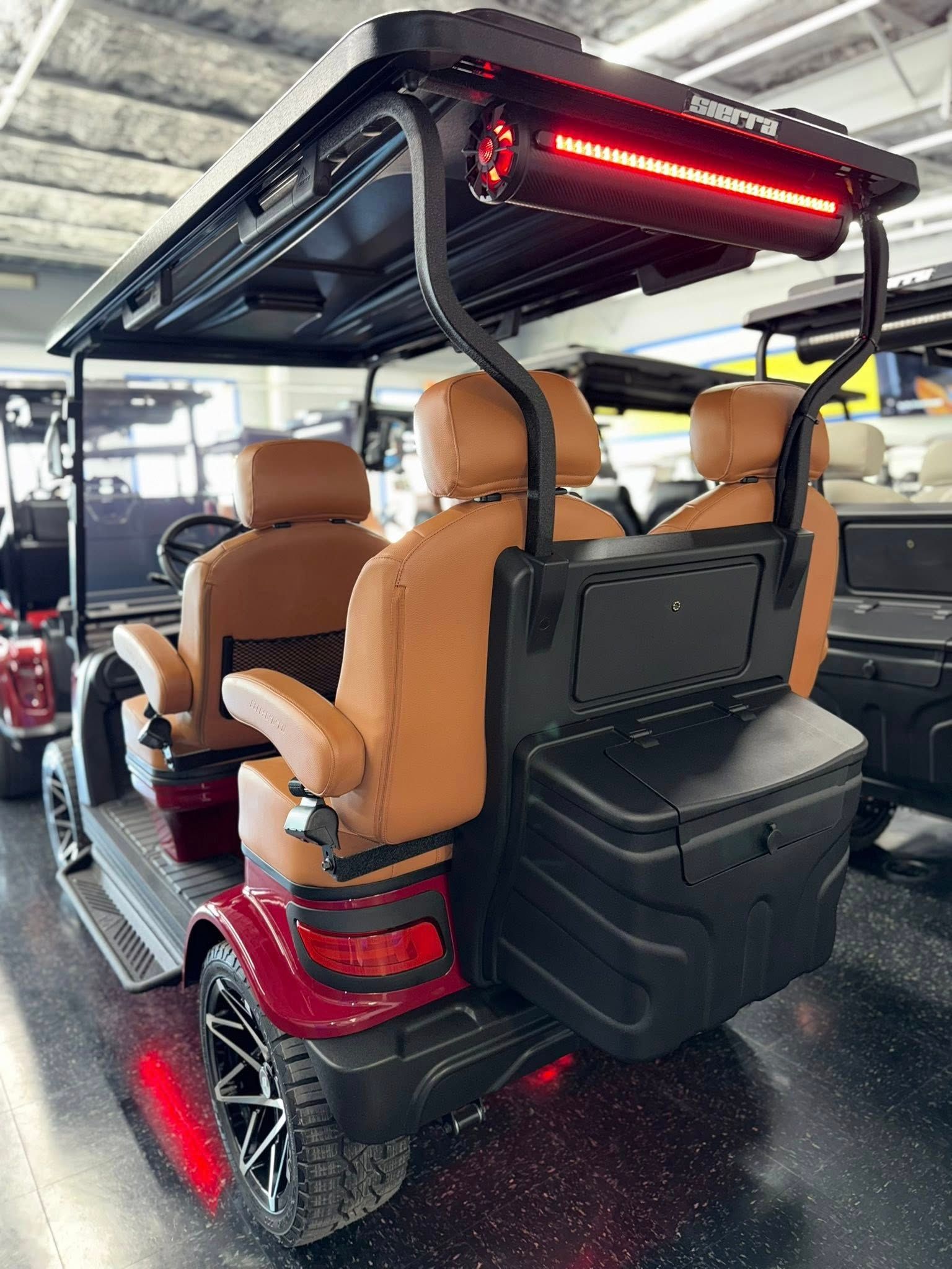 Red and black golf cart with brown seats, black storage, and a light bar.