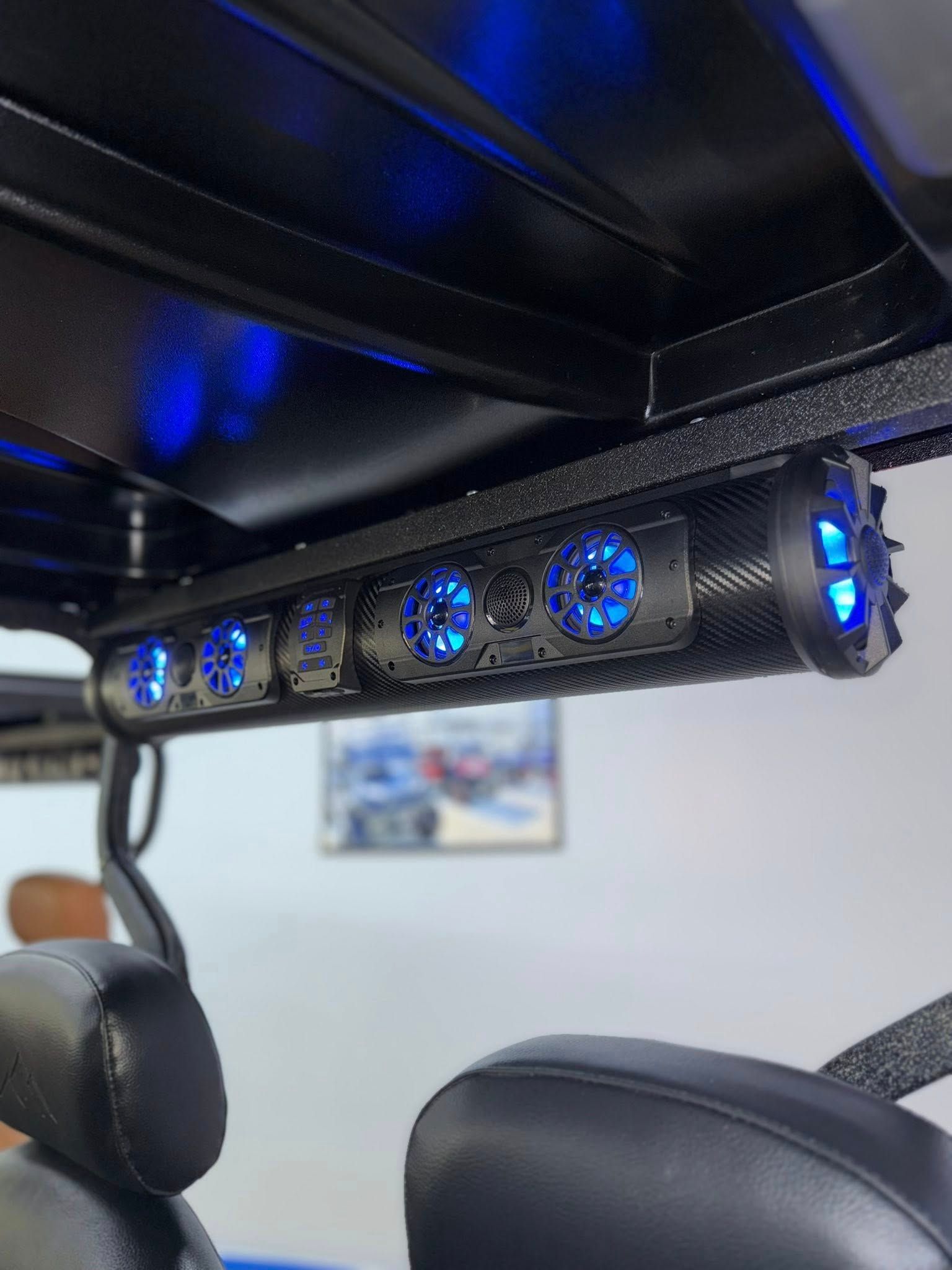 Golf cart interior with a black speaker bar featuring blue LED lights.
