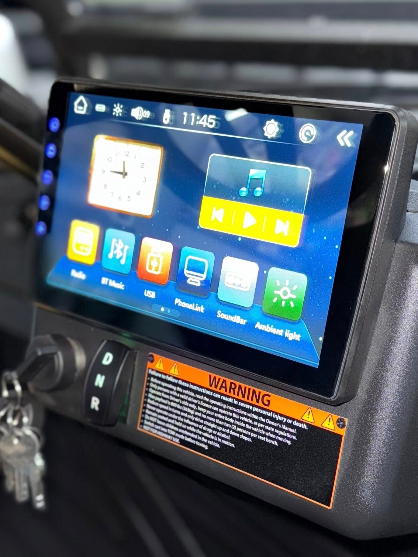 Dashboard with a touchscreen display. Shows a clock, media controls, and various app icons.