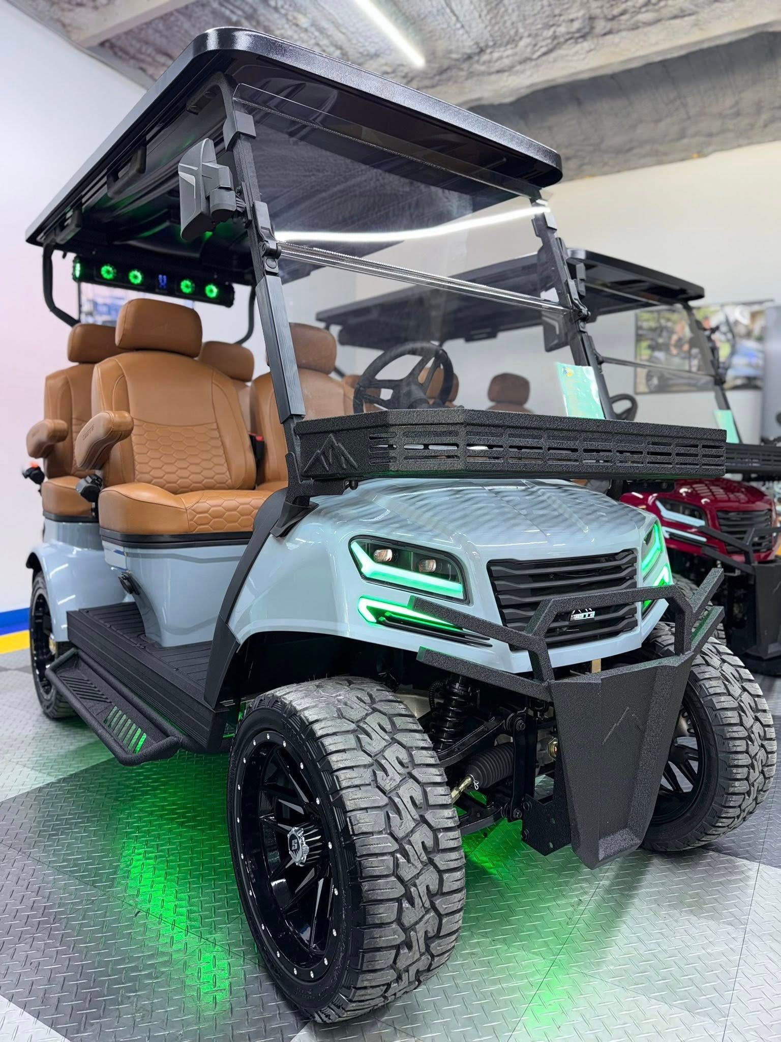 Gray golf cart with brown seats, black wheels and roof, lit with green lights.
