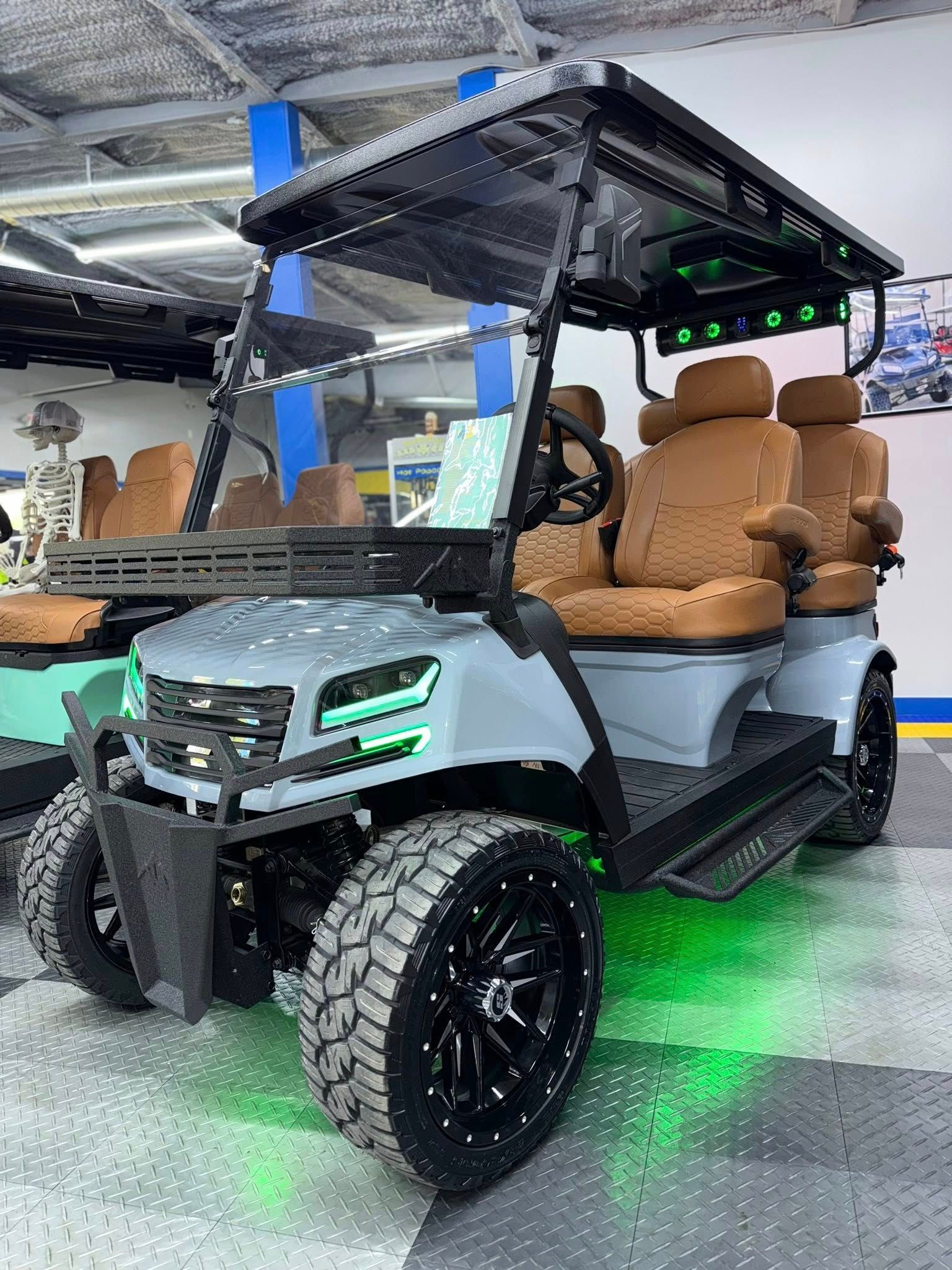 Custom grey golf cart with tan seats, large wheels, and green underglow lights.