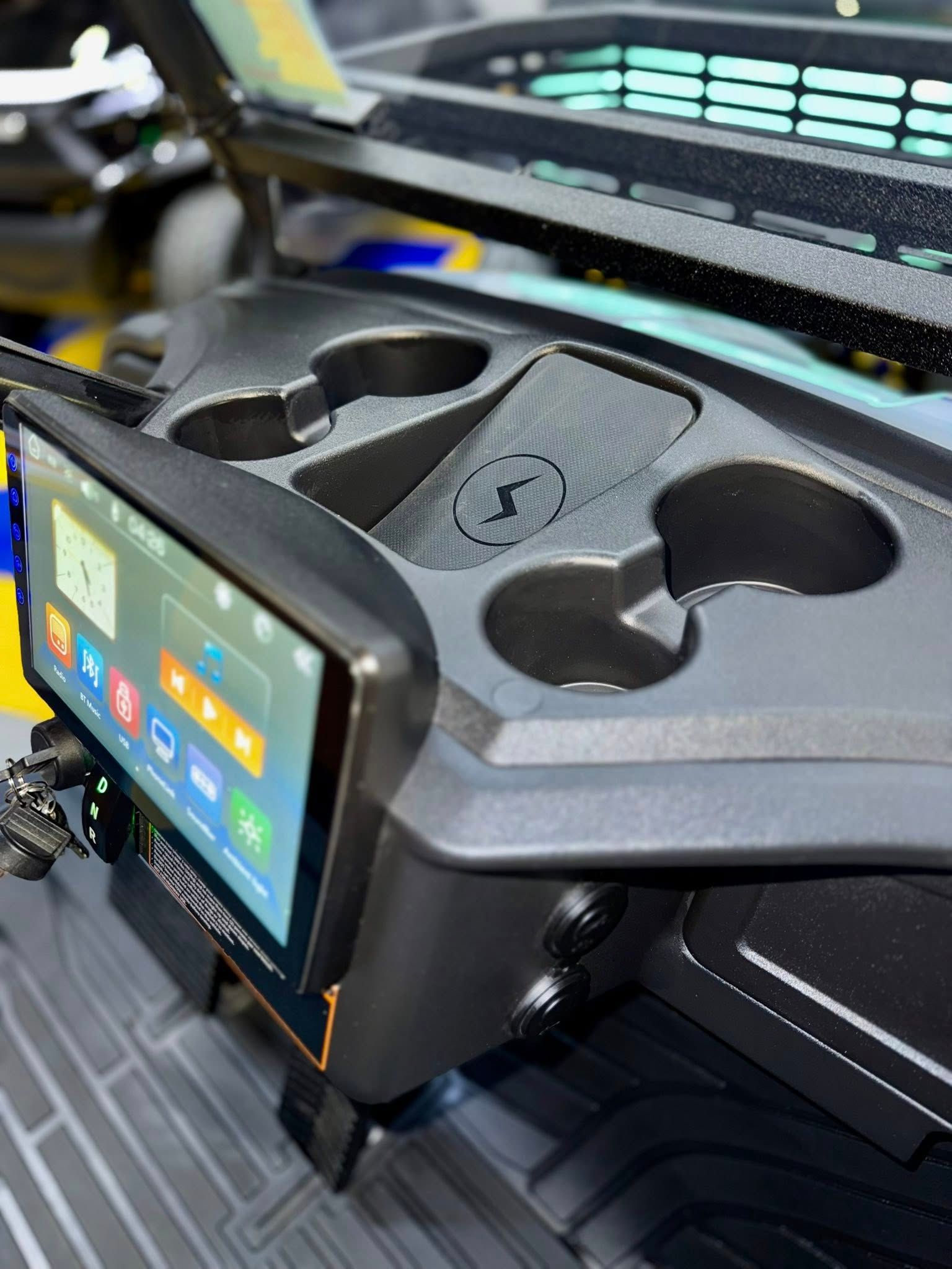 Golf cart dashboard with touchscreen, cupholders, and wireless charging pad.