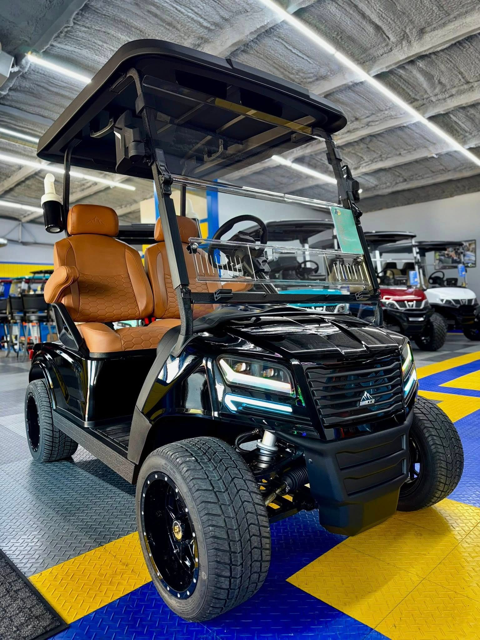 Black golf cart with brown seats, large wheels, and a black canopy, indoors.