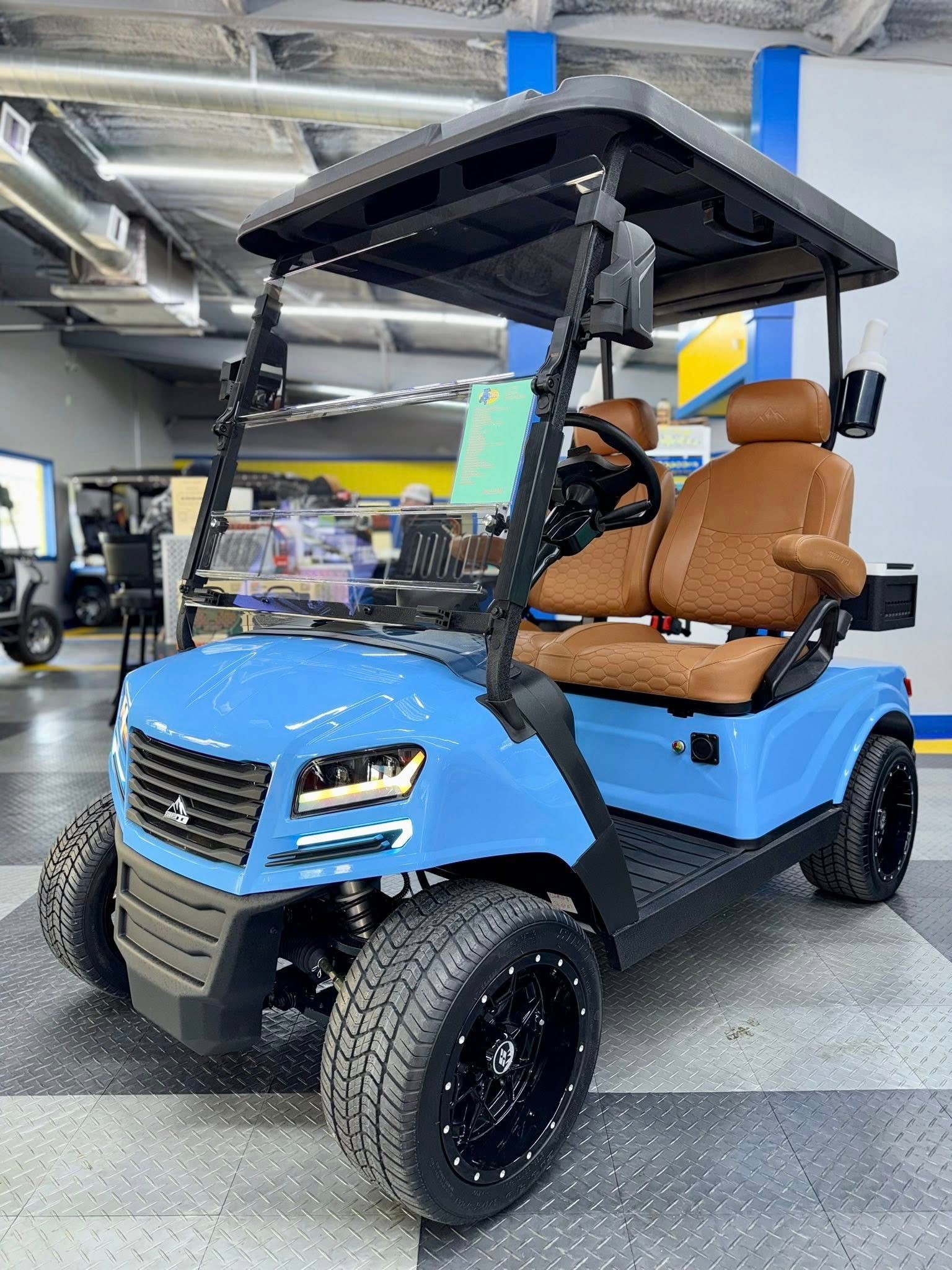 Blue golf cart with brown seats, black wheels, and a canopy in a showroom.