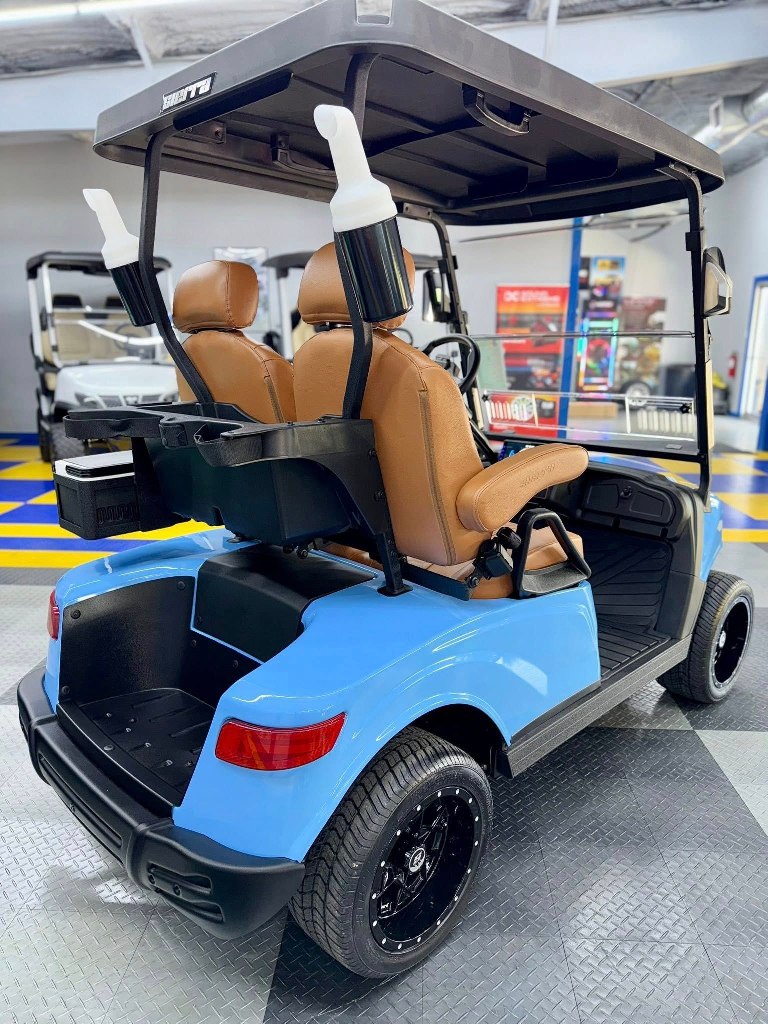 Blue golf cart with brown seats, black wheels, and a black roof inside a showroom.