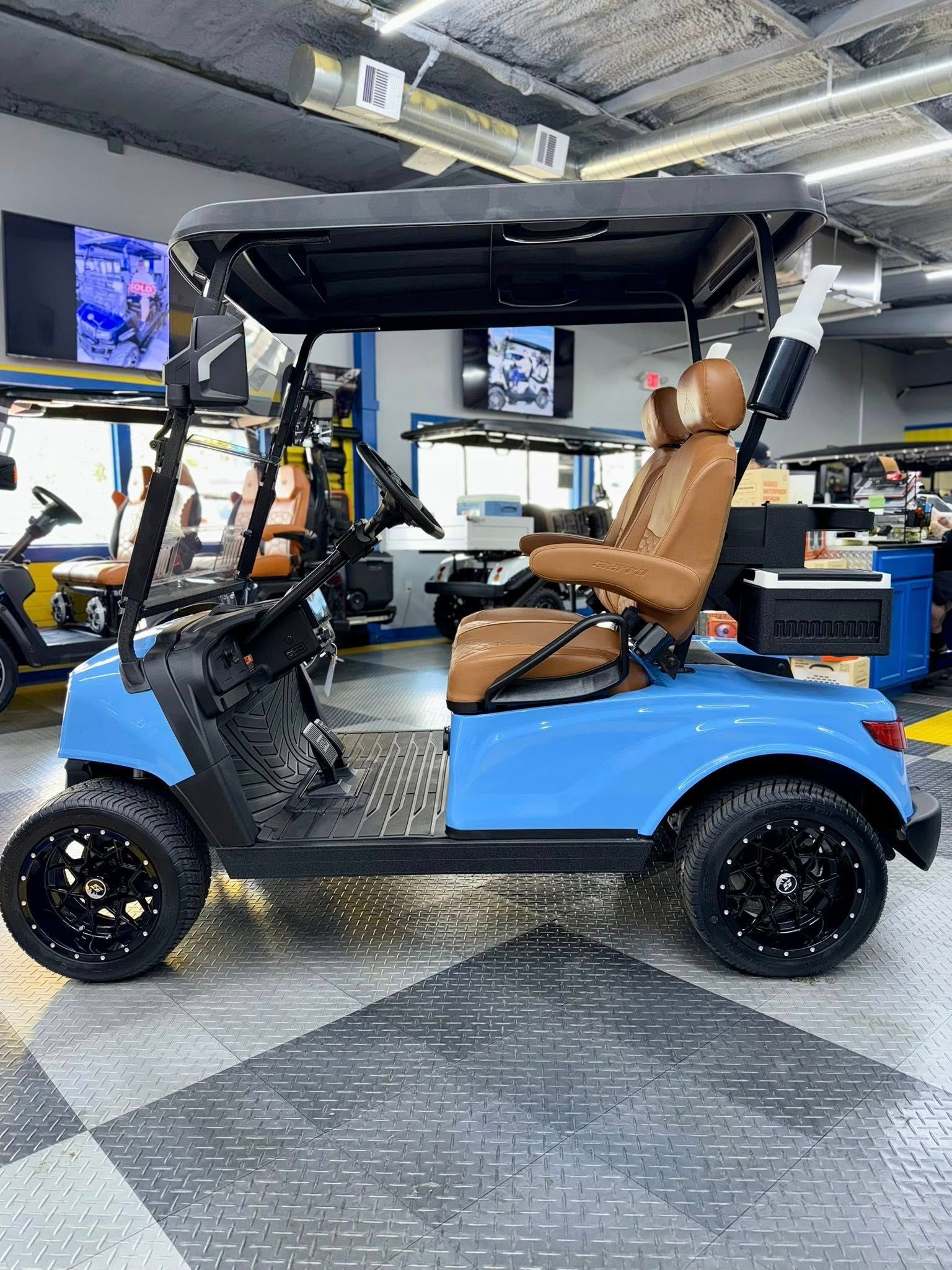 Blue golf cart with brown seats and black wheels parked inside a shop.