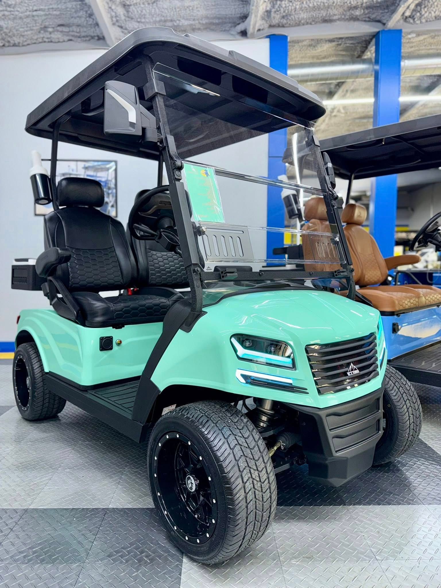 Mint green golf cart with black accents, black wheels, and canopy, indoors.