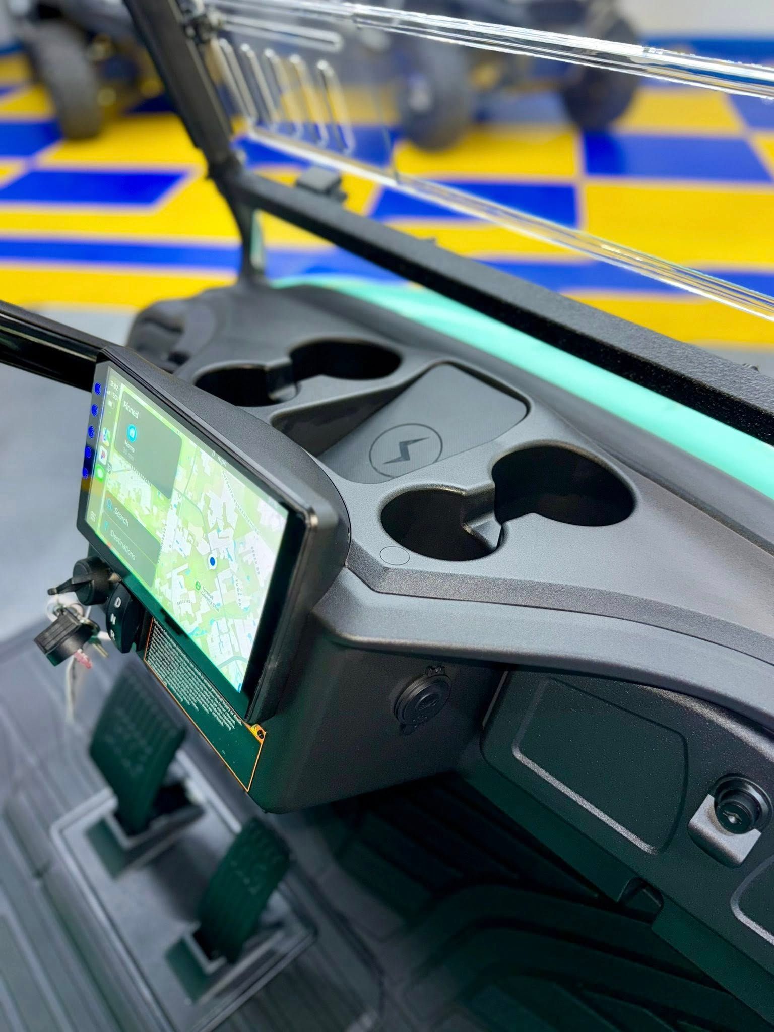 Golf cart dashboard with a mounted tablet displaying a map, cup holders, and control panel.