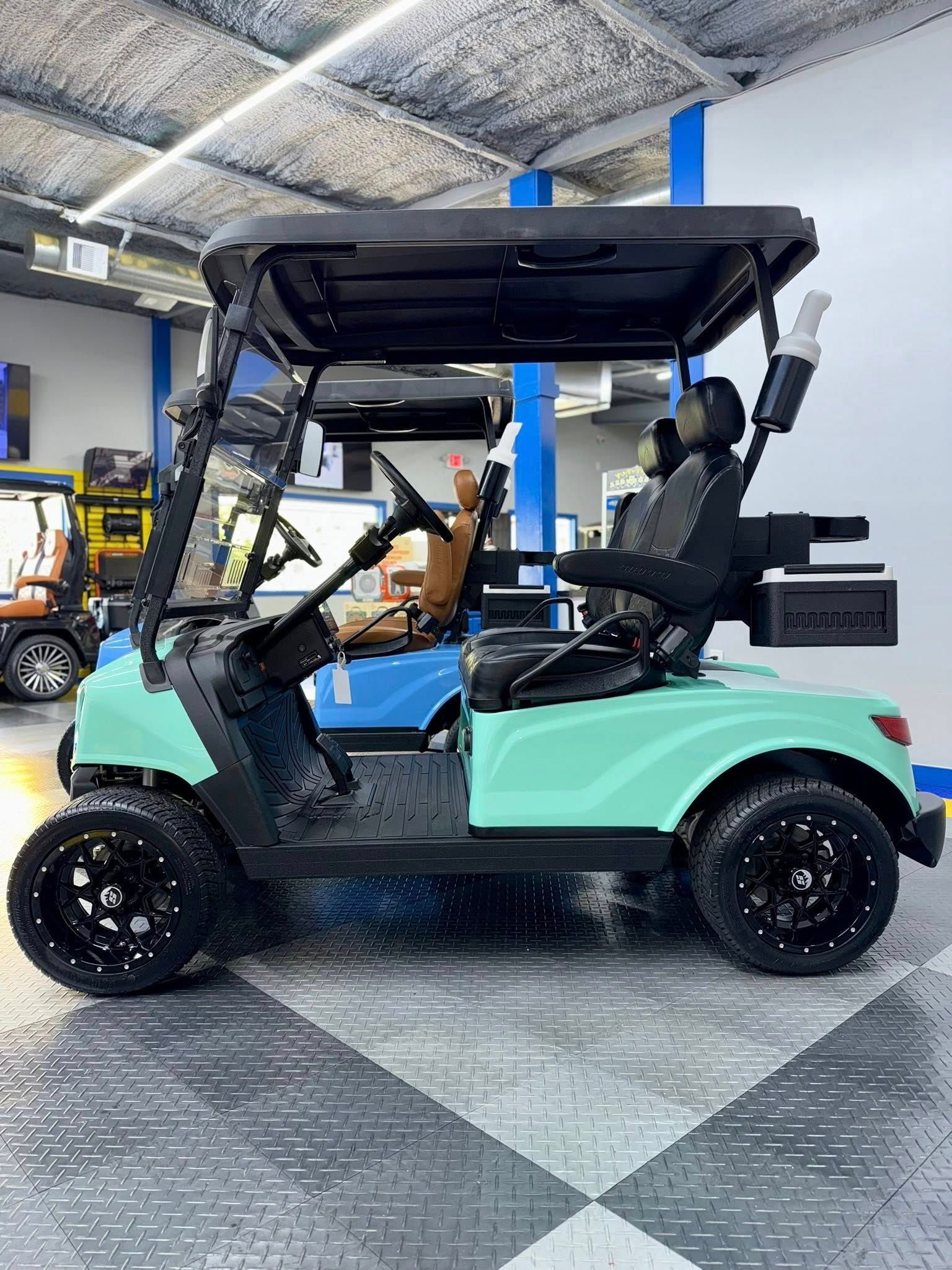 Mint green golf cart with black wheels and roof, inside a showroom.