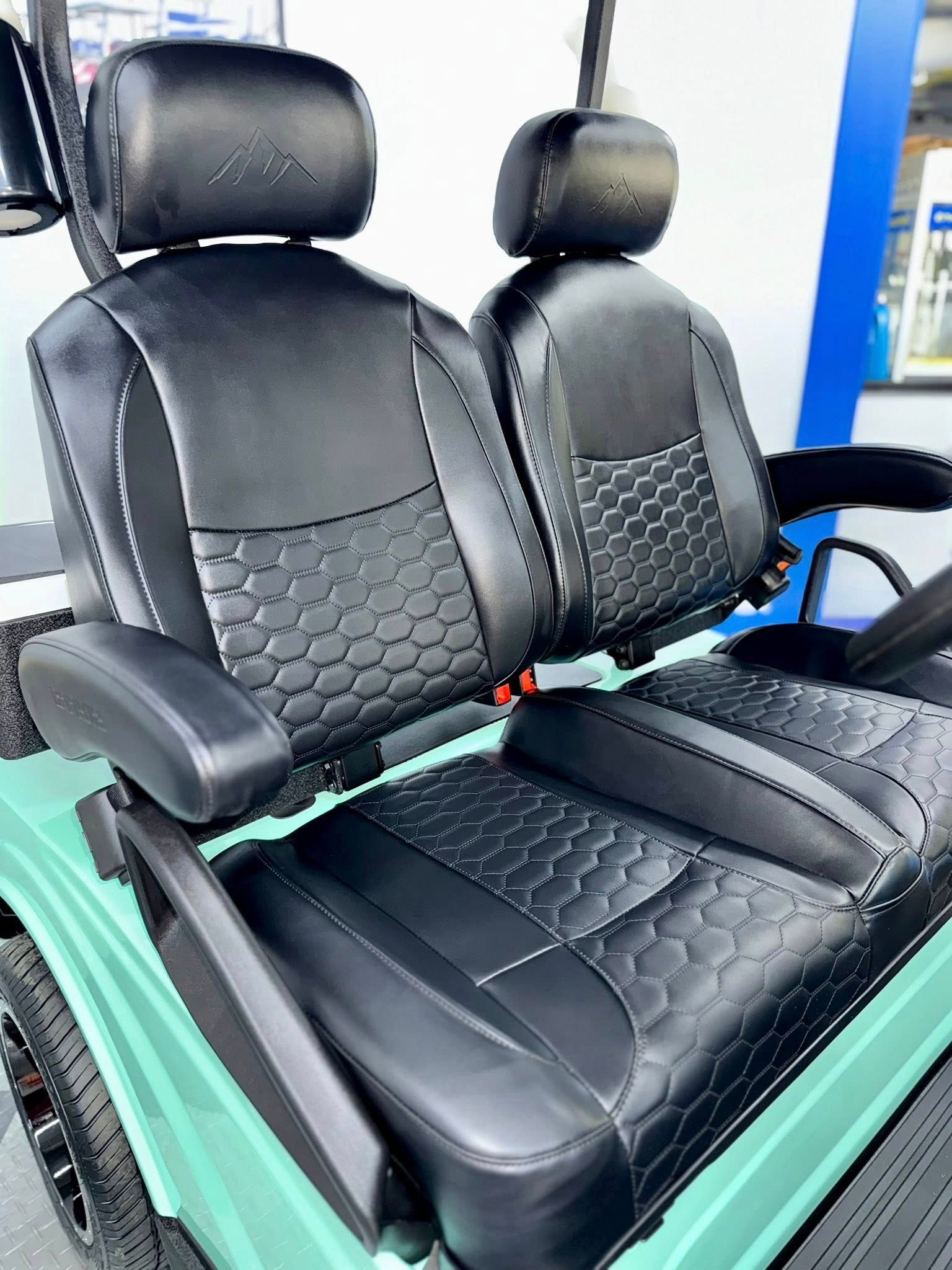 Black golf cart seats with diamond stitching, in a green golf cart.