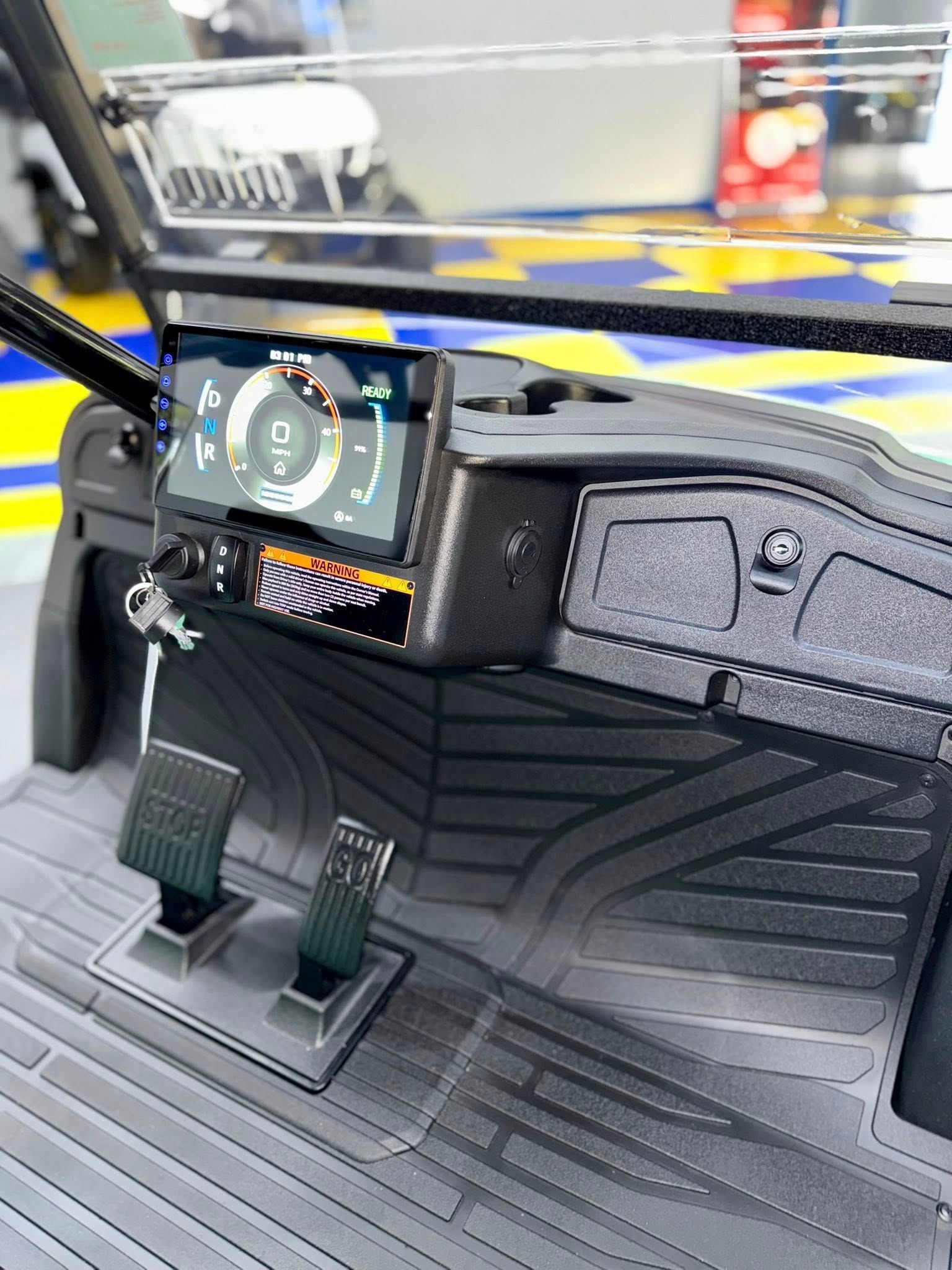 Golf cart dashboard with digital display, pedals, and key. Black and gray with a splash of color.