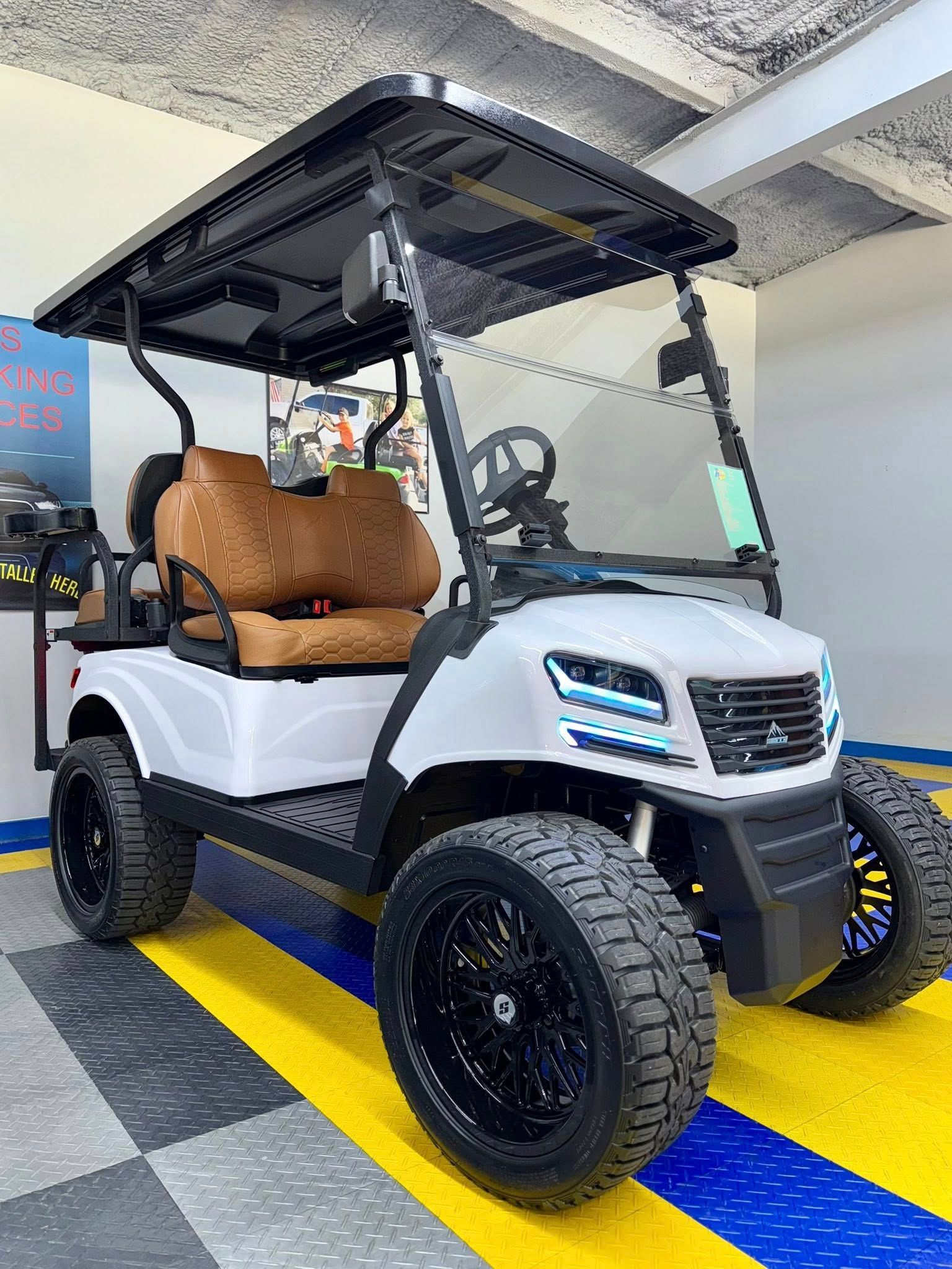 White golf cart with black wheels and a brown leather seat parked on a yellow and blue tiled floor.
