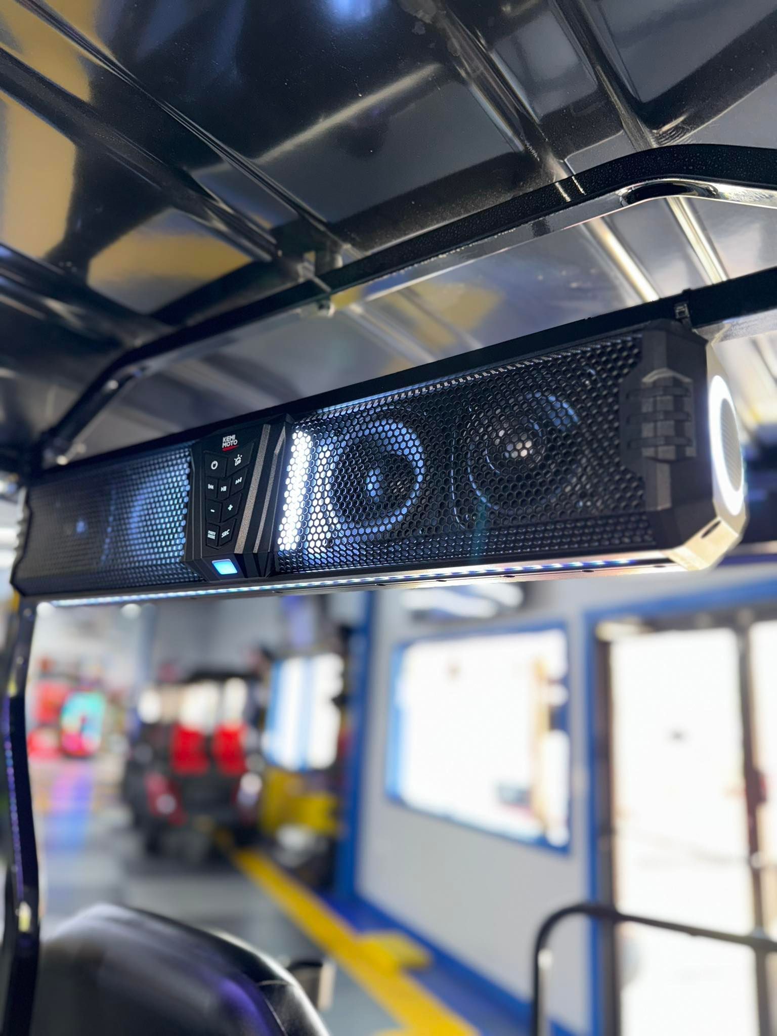 Black soundbar with illuminated lights mounted on the roof of a vehicle, in a garage.