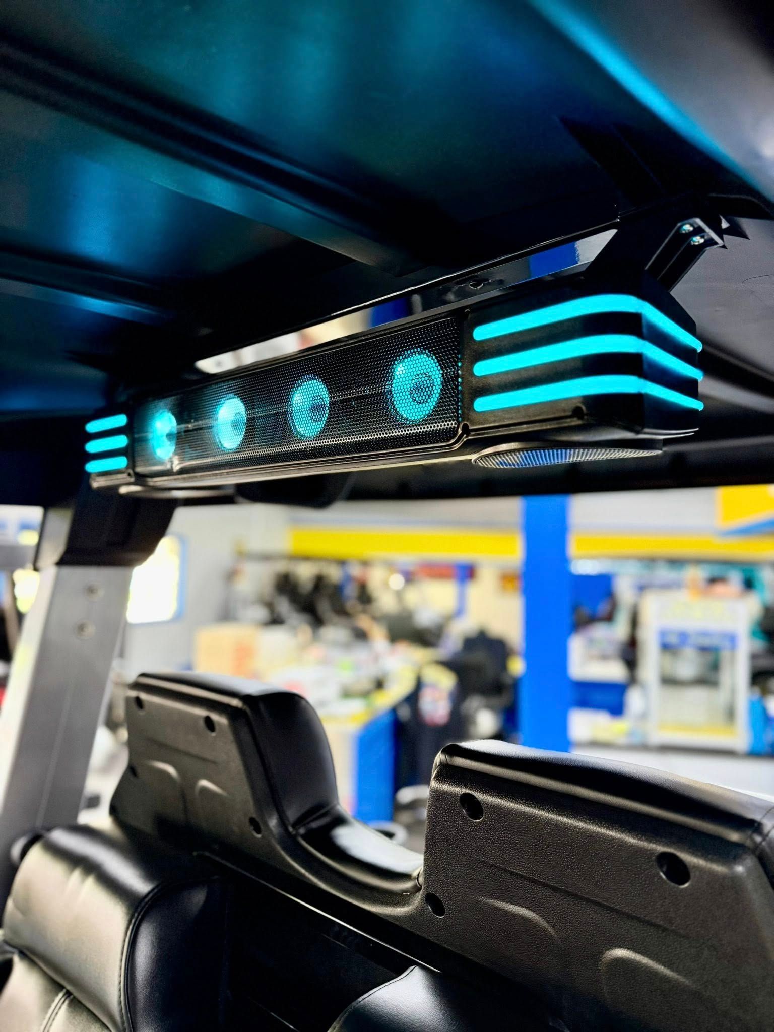 Golf cart interior with blue LED lights. Black seats and light bar, a shop background.