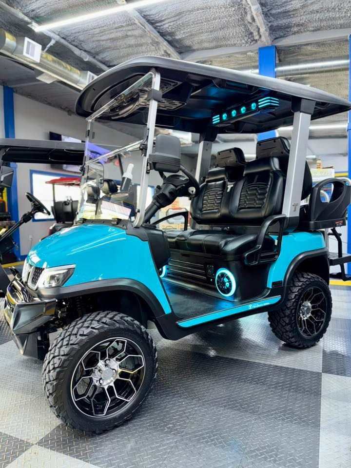 Blue and black custom golf cart with black wheels, lit up, indoors.
