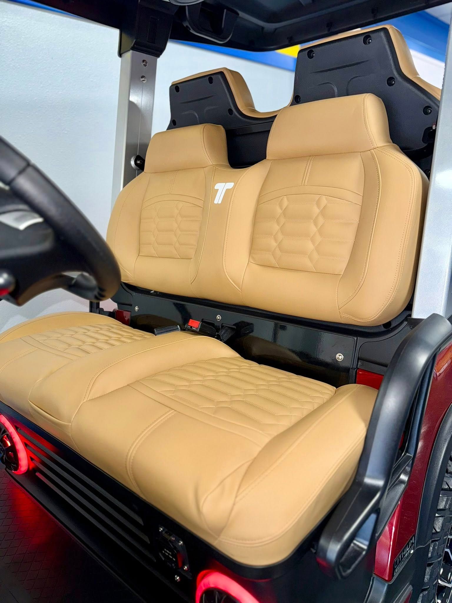 Tan leather golf cart seats with a black frame and red accents.