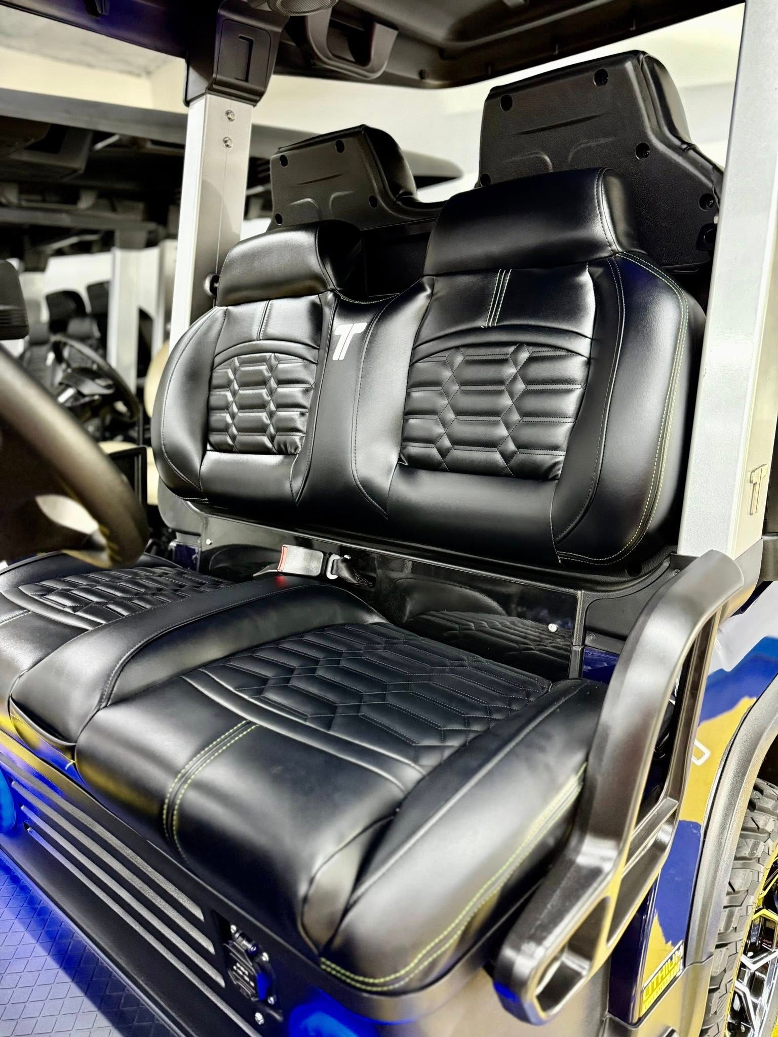 Black golf cart seats with detailed stitching, set inside a partially visible golf cart.