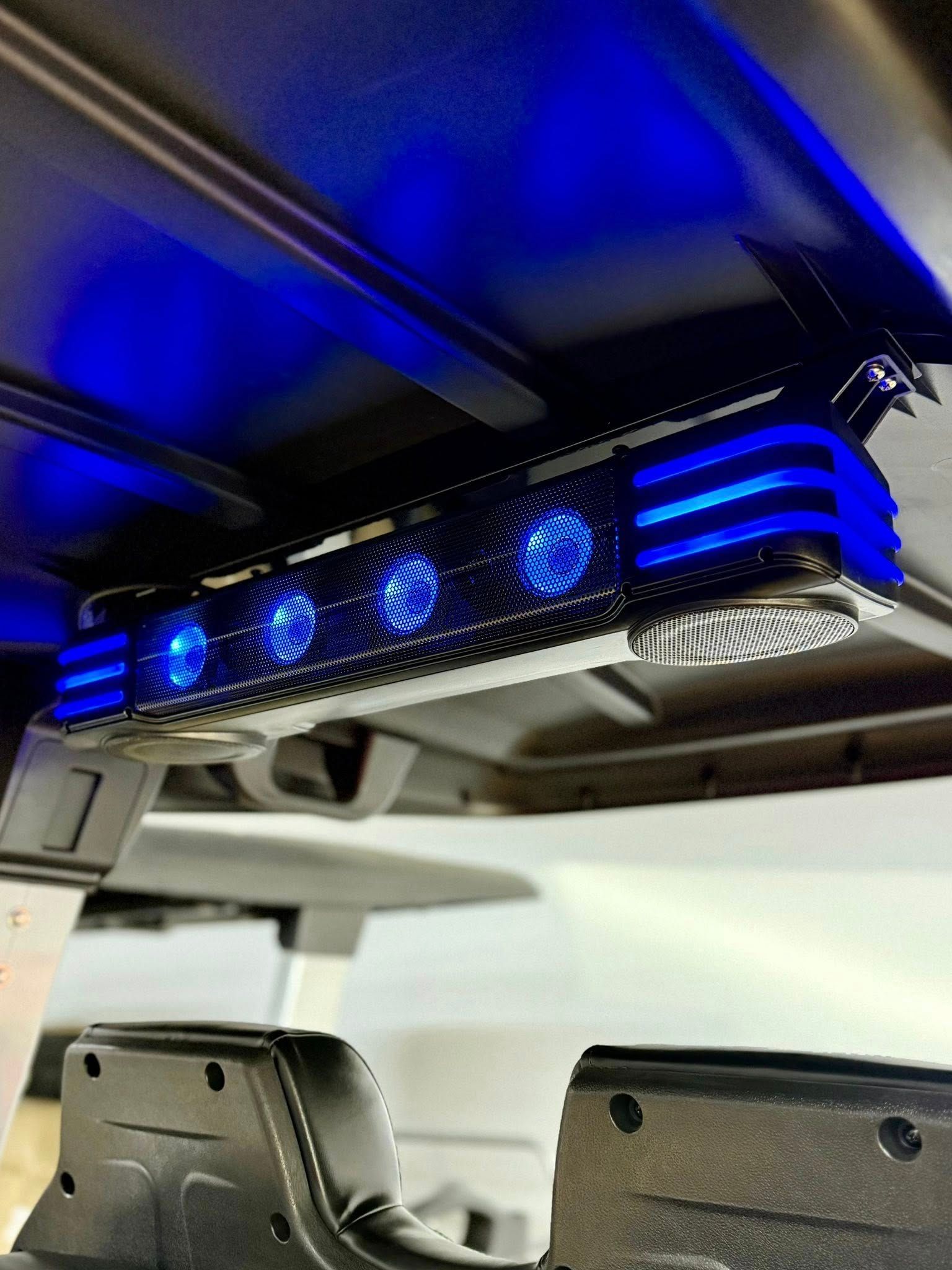 Blue-lit golf cart sound bar mounted under the roof, visible from a low angle above the seats.