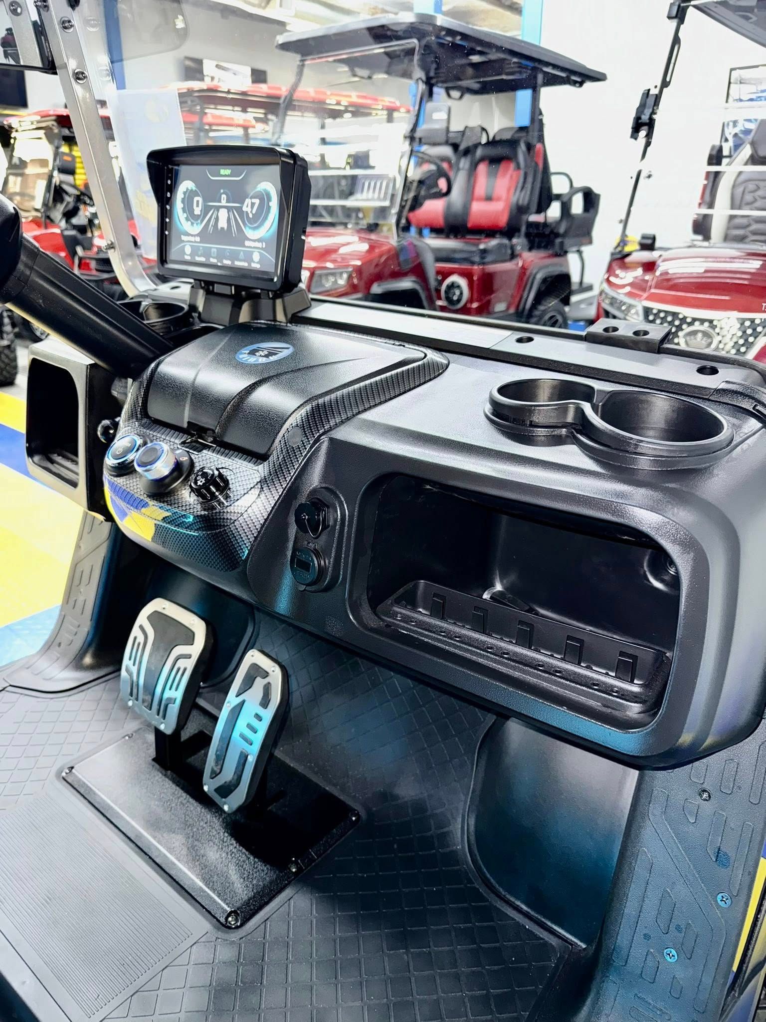 Black golf cart dashboard with digital display, cupholders, and blue-lit pedals.