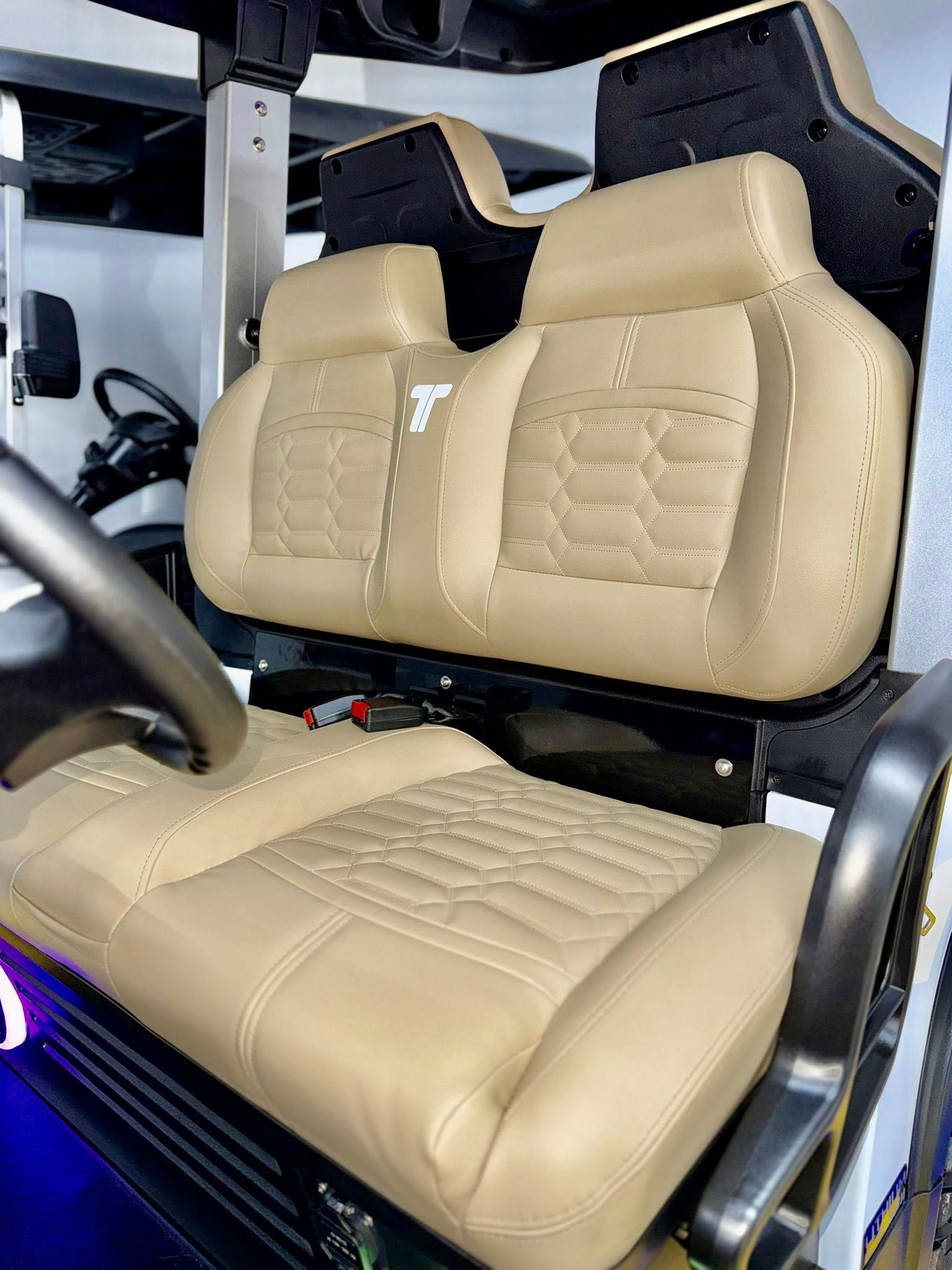 Tan golf cart seats with intricate stitching, showcasing a stylized