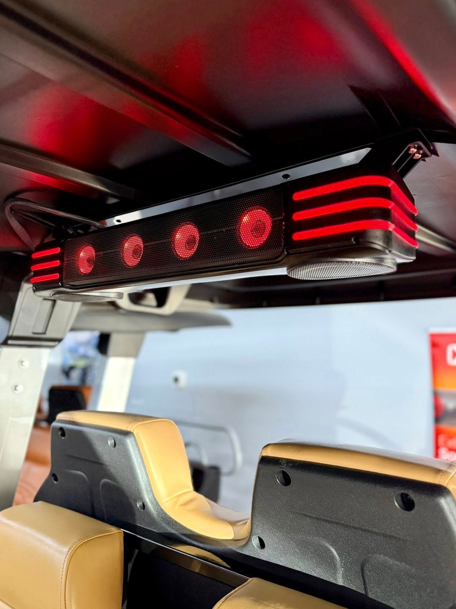 Red LED light bar installed in the ceiling of a golf cart. The seats are tan and black.