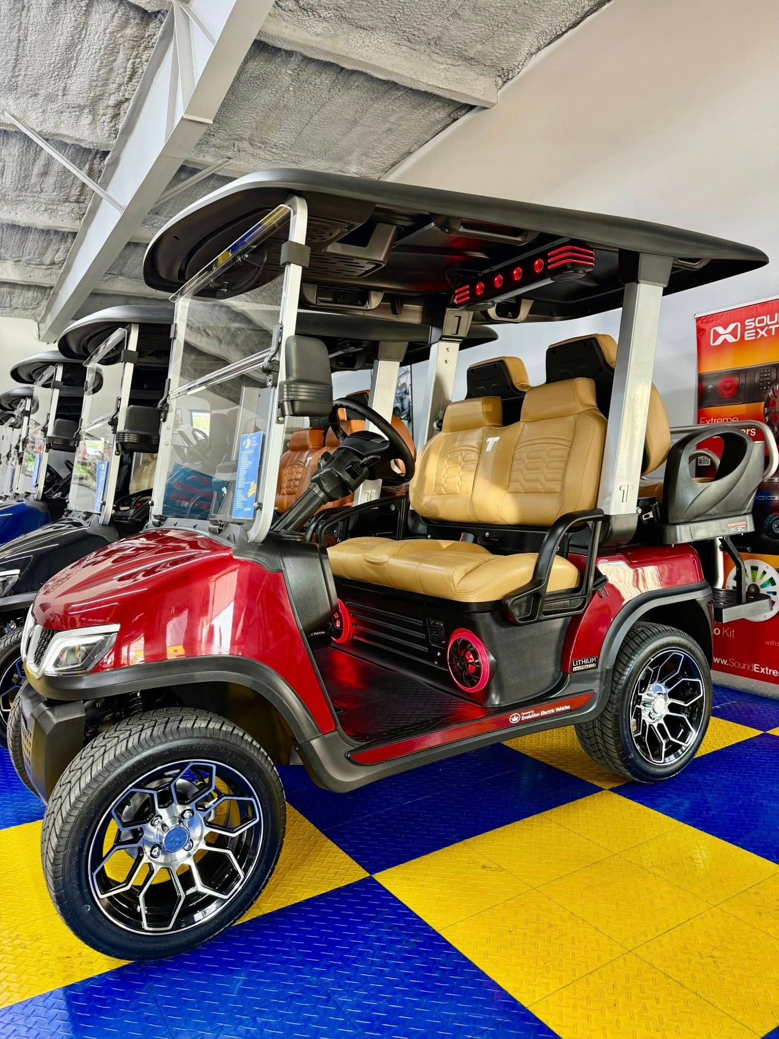 Red and black golf cart with tan seats, black wheels, parked on a blue and yellow checkered floor.
