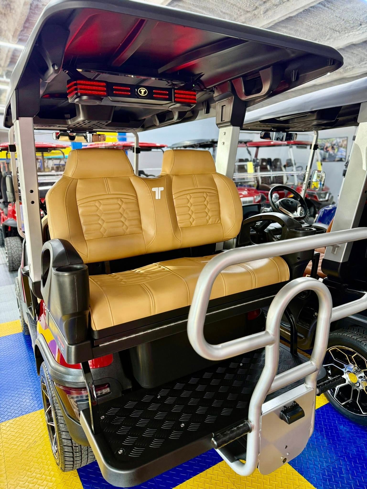 Rear view of a customized golf cart with tan leather seats, a black body, and a silver handrail.