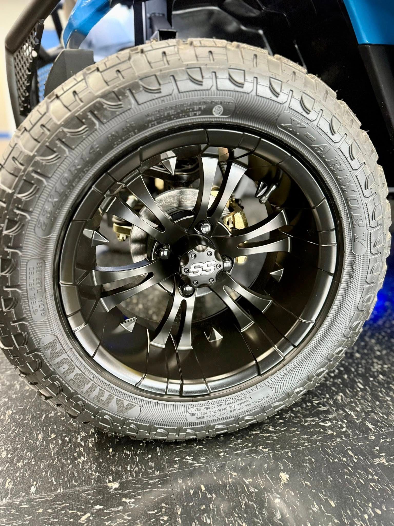 Black golf cart wheel with rugged tire on a black rim.