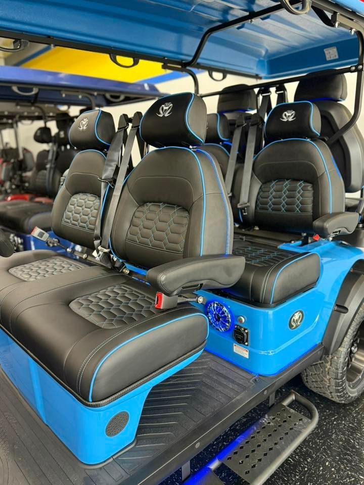 Blue and black golf cart with custom seats, blue accents, and large tires.
