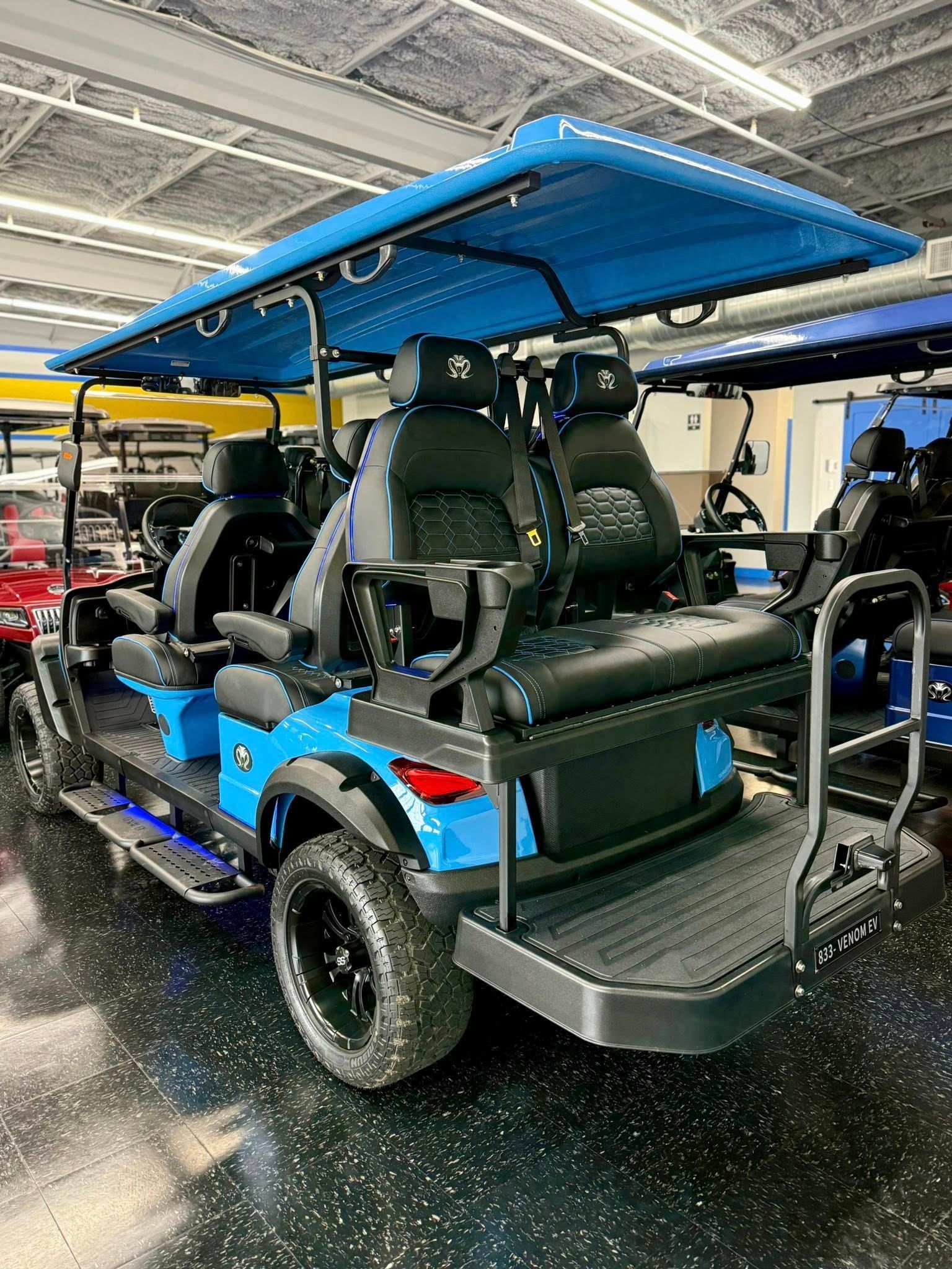 Blue lifted golf cart with black seats and roof, parked indoors.