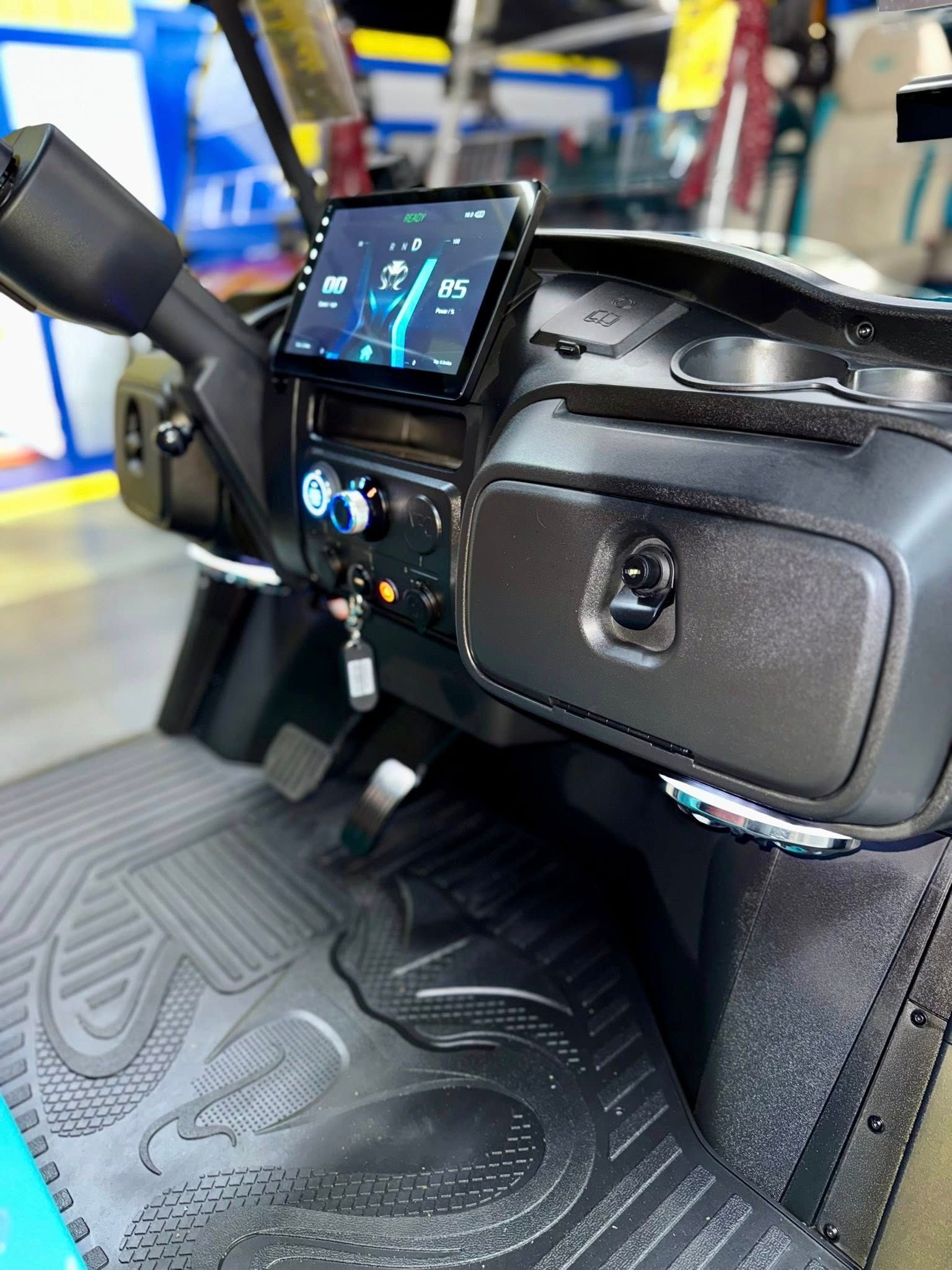 Dashboard of a golf cart with a digital display, cup holders, and a key.