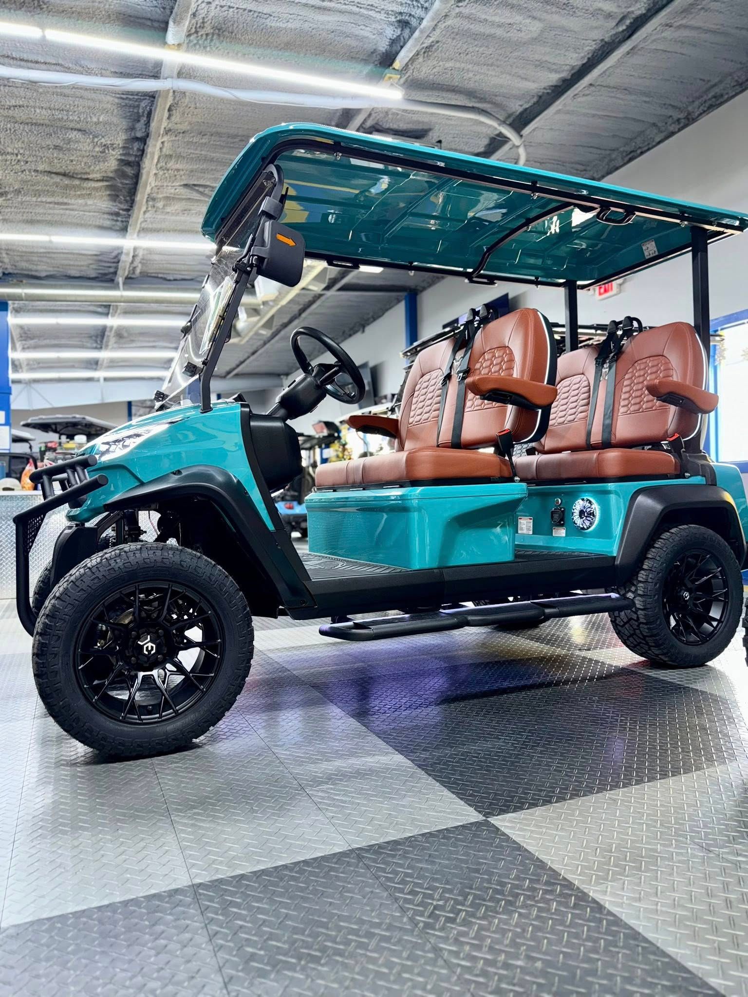 Teal golf cart with brown seats, black wheels, and a teal canopy parked on a checkered floor.