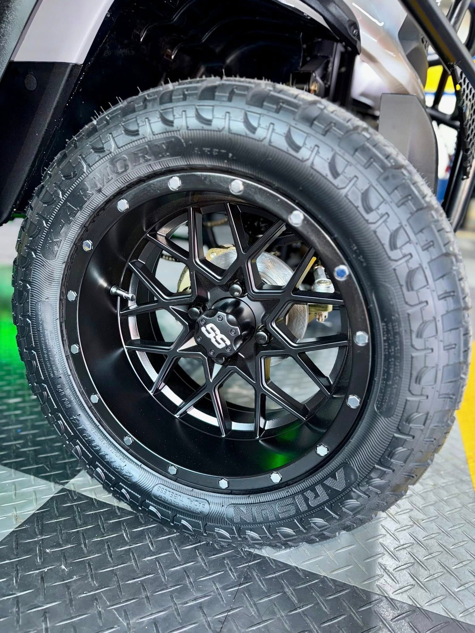 Black golf cart wheel with off-road tire.