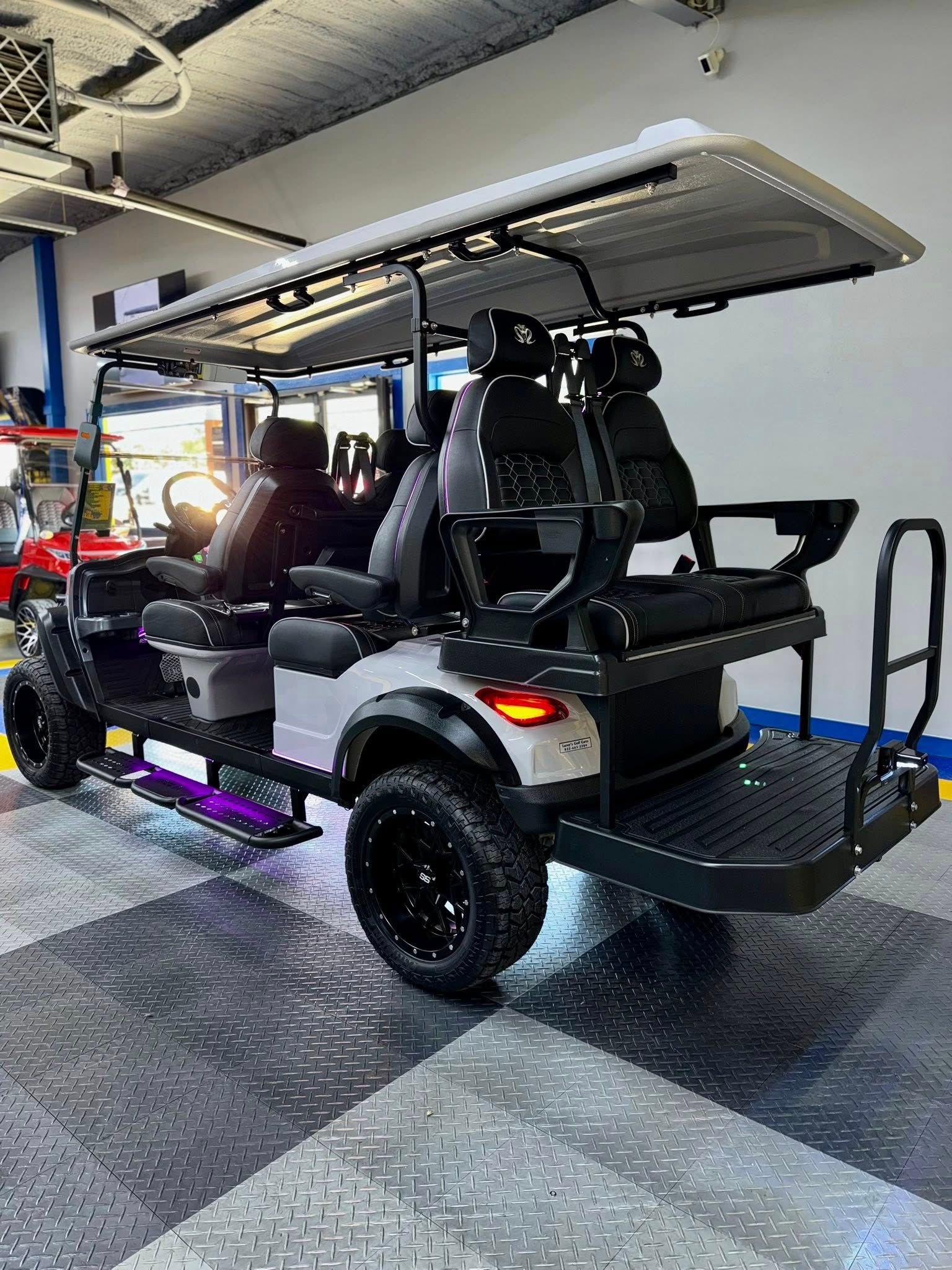 Gray and black custom golf cart with lifted wheels, rear seating, and LED lights.