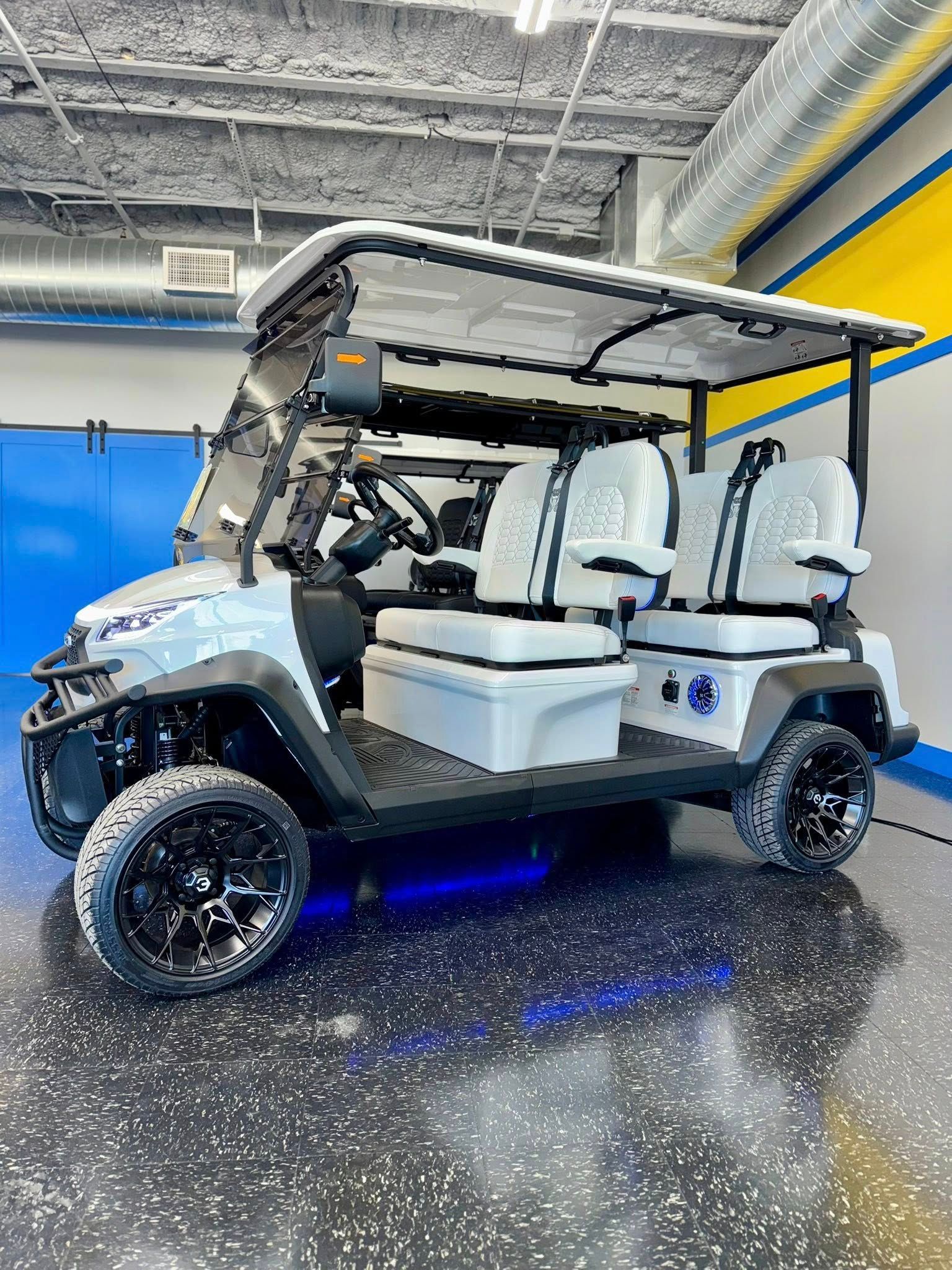 White golf cart with black accents, custom seats, and underglow lights.
