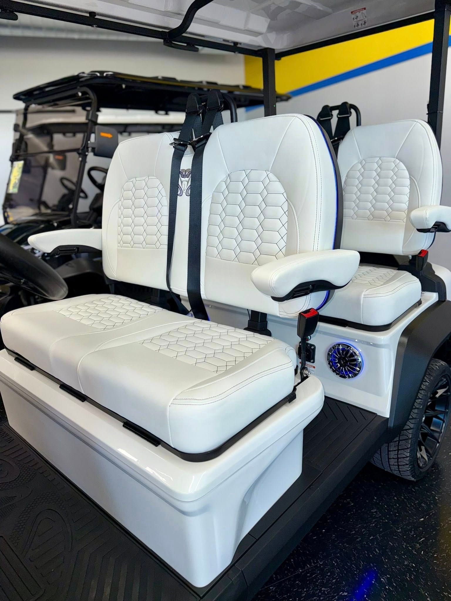 White golf cart with custom seats, black trim, and a white storage box.